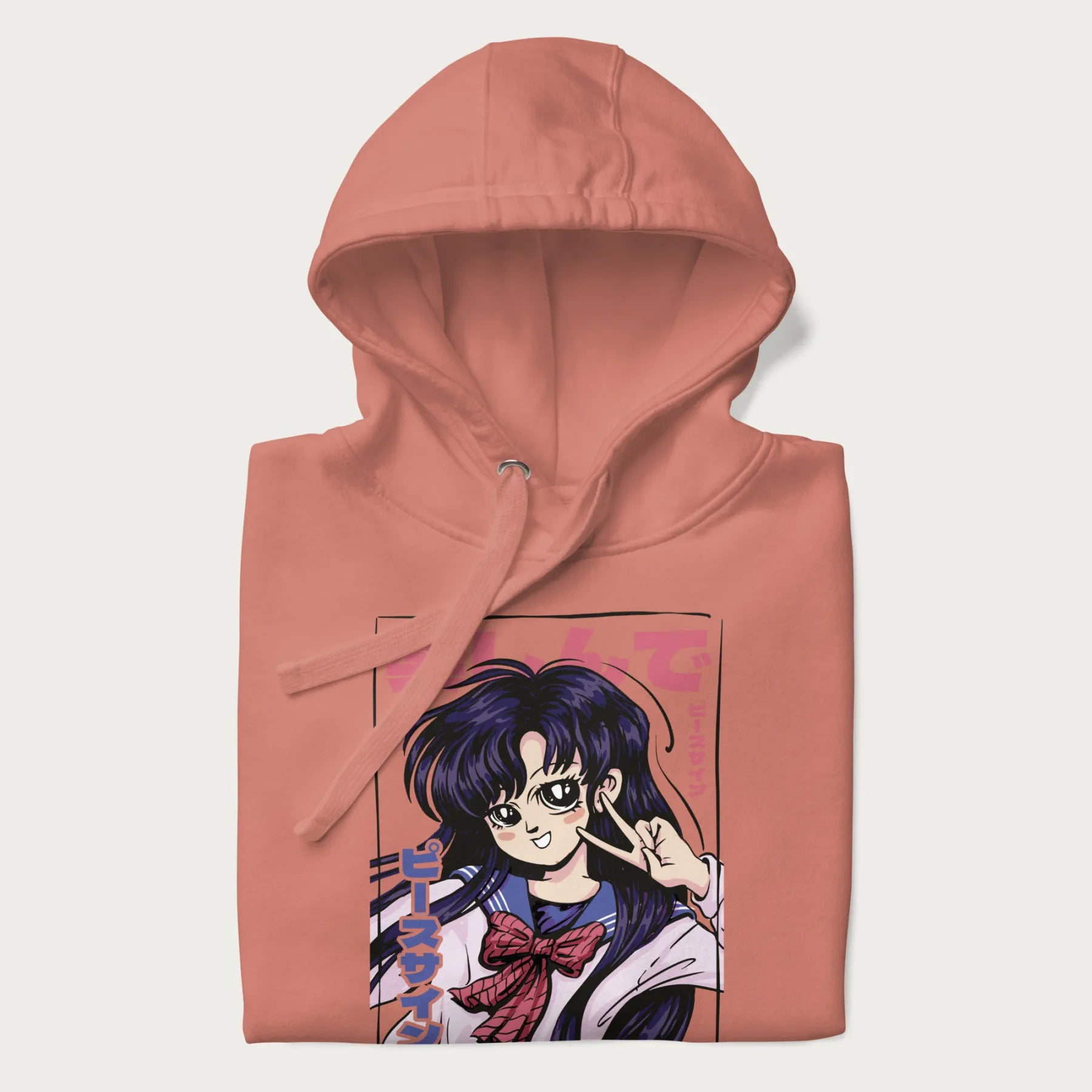 Folded light pink hoodie with Japanese graphic of an anime girl making a peace sign, with Japanese text '楽しんで' (Enjoy) and 'ピースサイン' (Peace Sign).