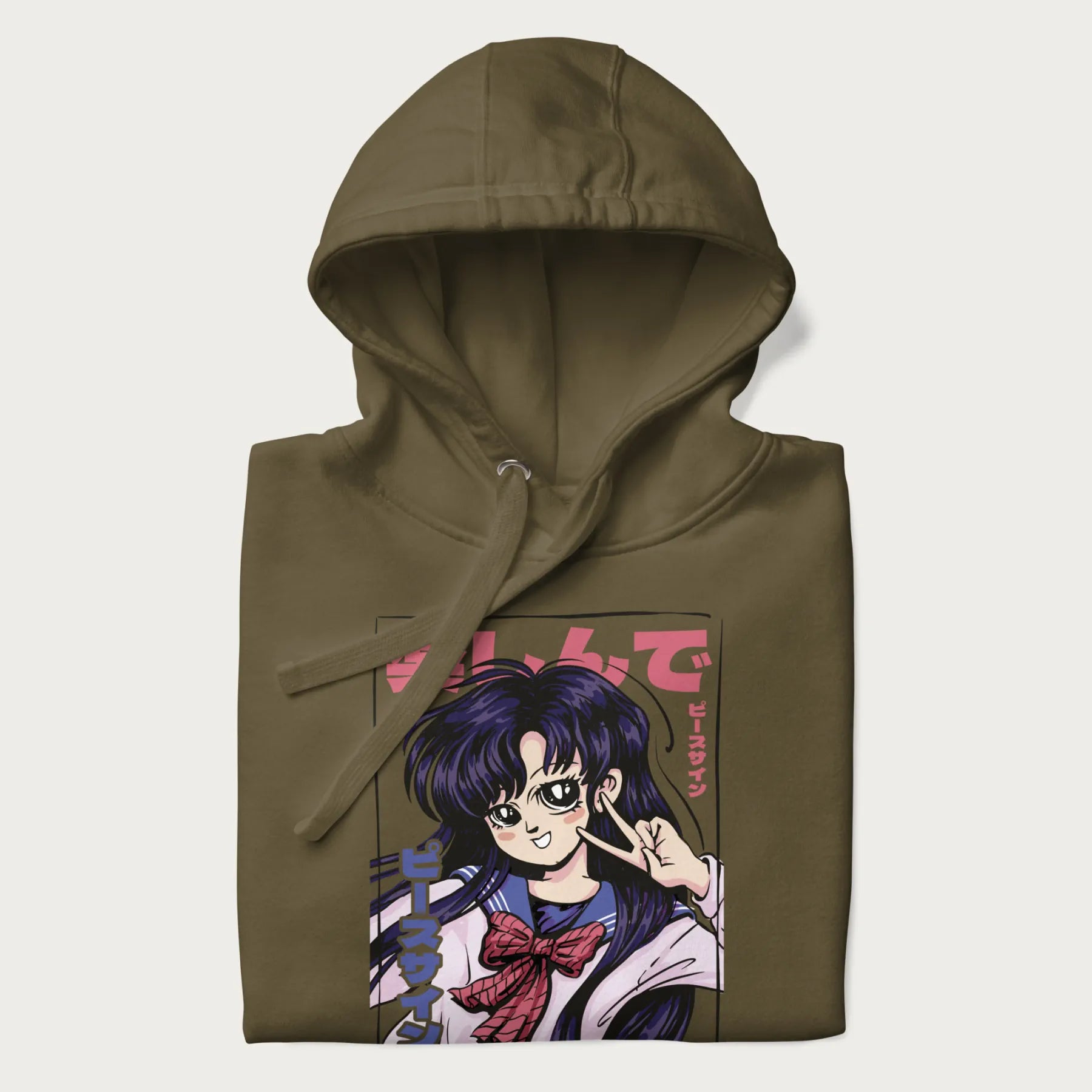 Folded military green hoodie with Japanese graphic of an anime girl making a peace sign, with Japanese text '楽しんで' (Enjoy) and 'ピースサイン' (Peace Sign).