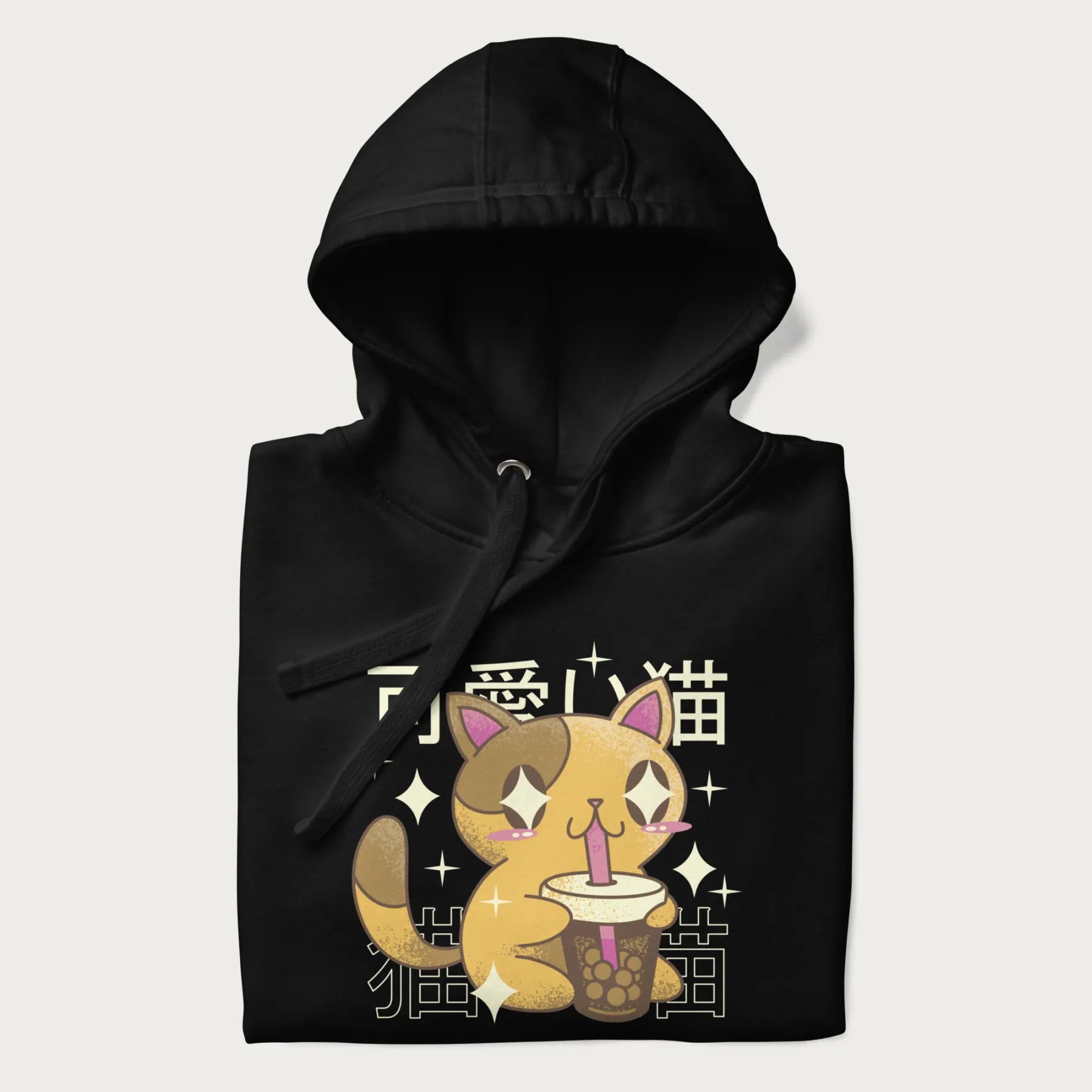 Folded black hoodie with Japanese graphic of a cute yellow cat drinking bubble tea, with the Japanese text '可愛い猫' (Cute Cat) in the background.