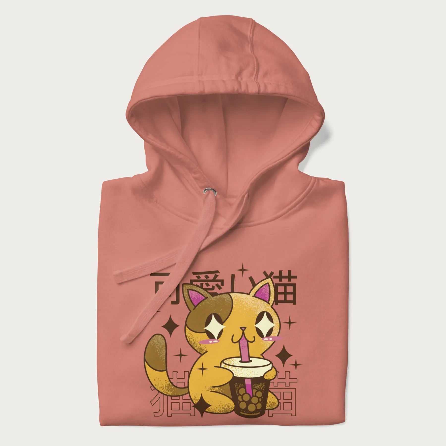 Folded light pink hoodie with Japanese graphic of a cute yellow cat drinking bubble tea, with the Japanese text '可愛い猫' (Cute Cat) in the background.