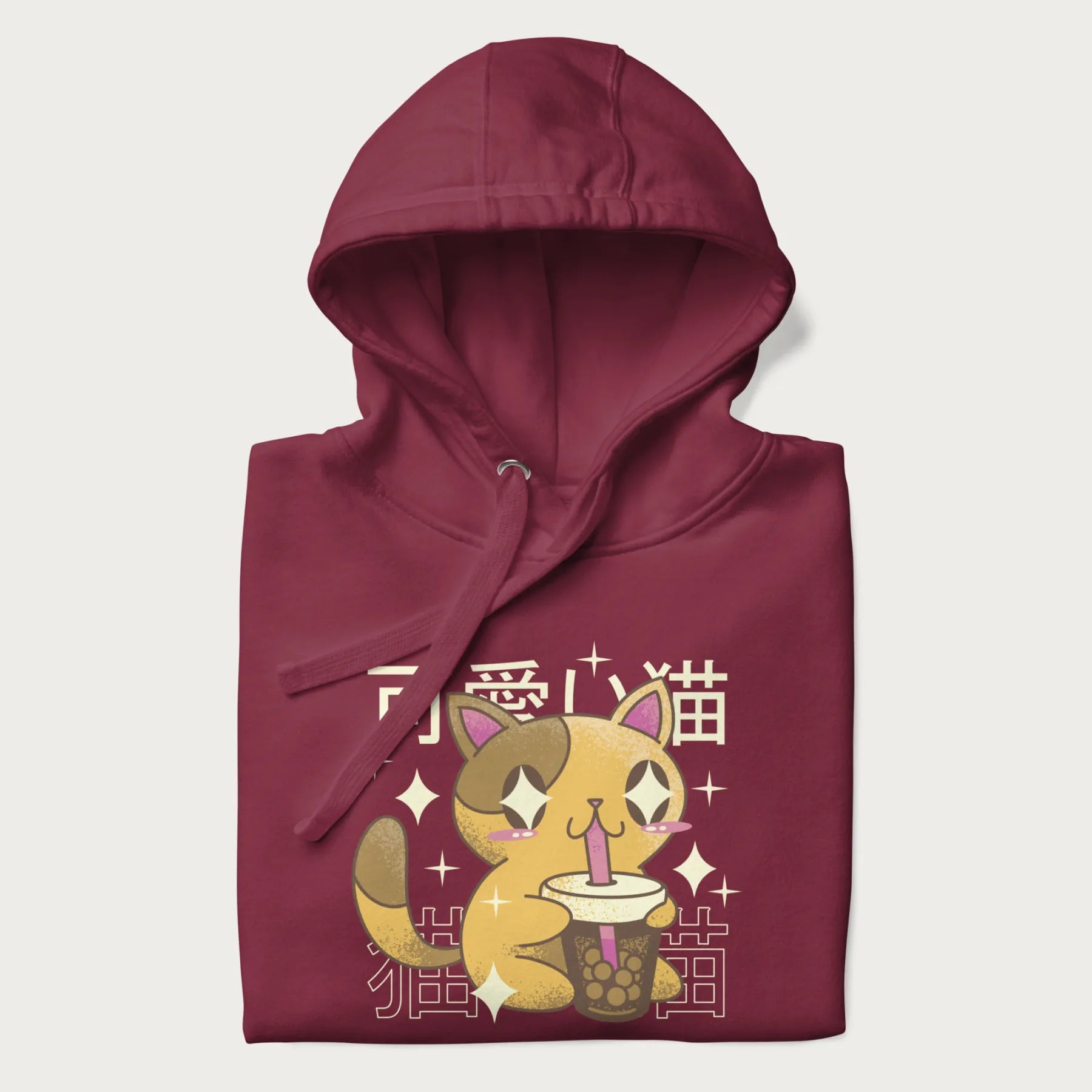 Folded maroon hoodie with Japanese graphic of a cute yellow cat drinking bubble tea, with the Japanese text '可愛い猫' (Cute Cat) in the background.