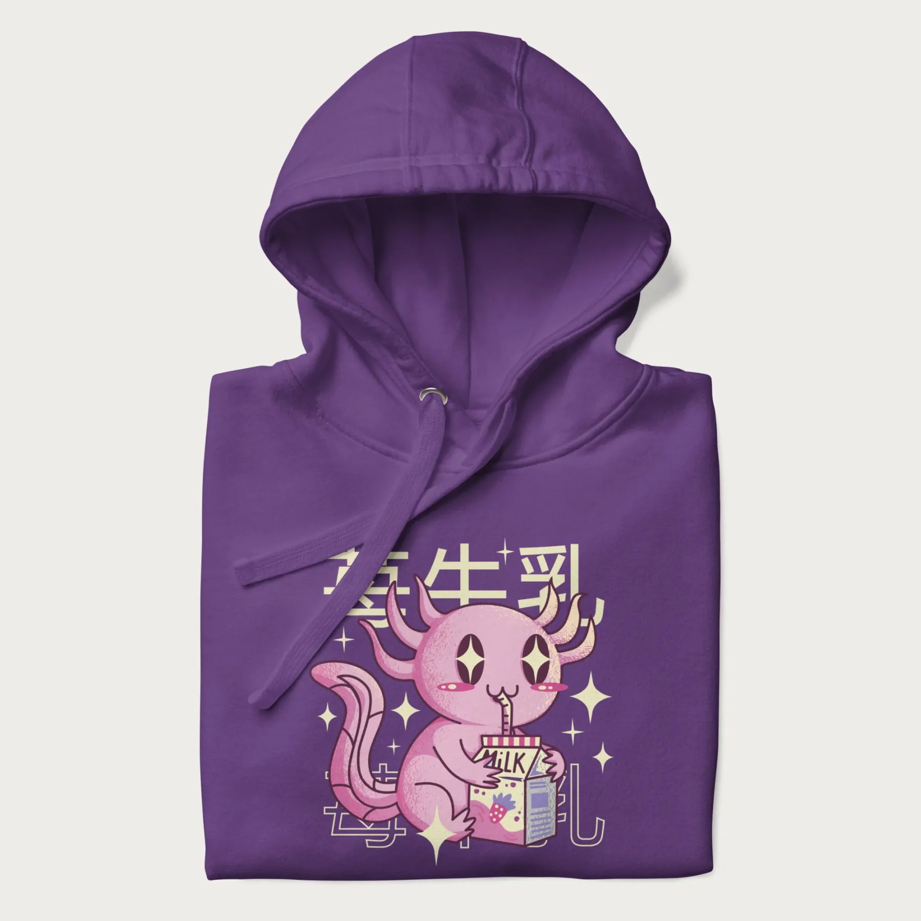 Folded purple hoodie with Japanese graphic of a cute pink axolotl sipping strawberry milk from a carton, with Japanese text '苺牛乳' (Strawberry Milk).