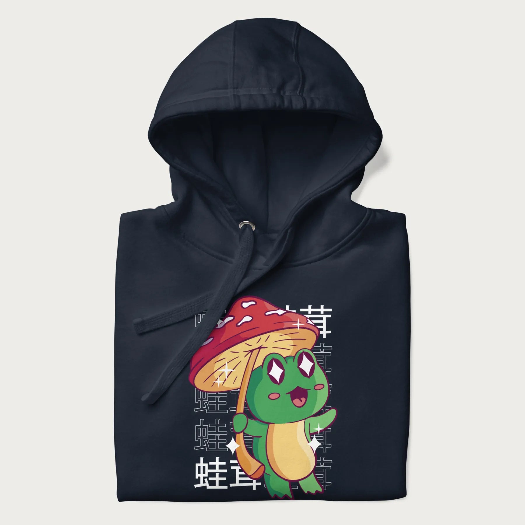 Folded navy blue hoodie with Japanese graphic of a cute green frog holding a red mushroom and Japanese text '蛙茸' in the background.