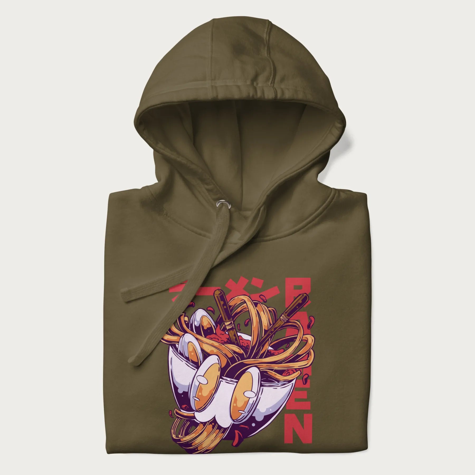 Folded military green hoodie with Japanese graphic of a ramen bowl with noodles, eggs and Japanese text 'ラーメン' (Ramen) in bold red text.