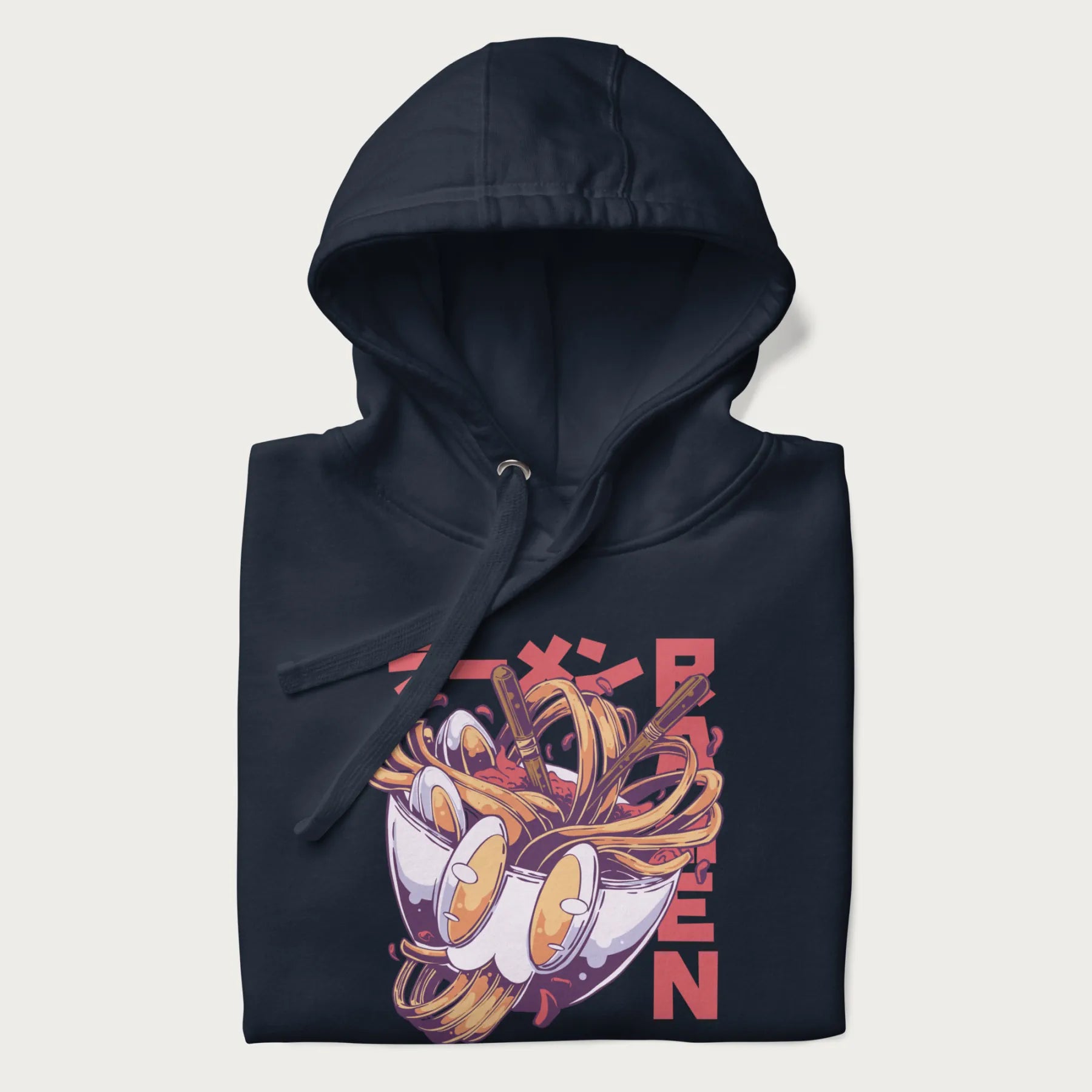 Folded navy blue hoodie with Japanese graphic of a ramen bowl with noodles, eggs and Japanese text 'ラーメン' (Ramen) in bold red text.