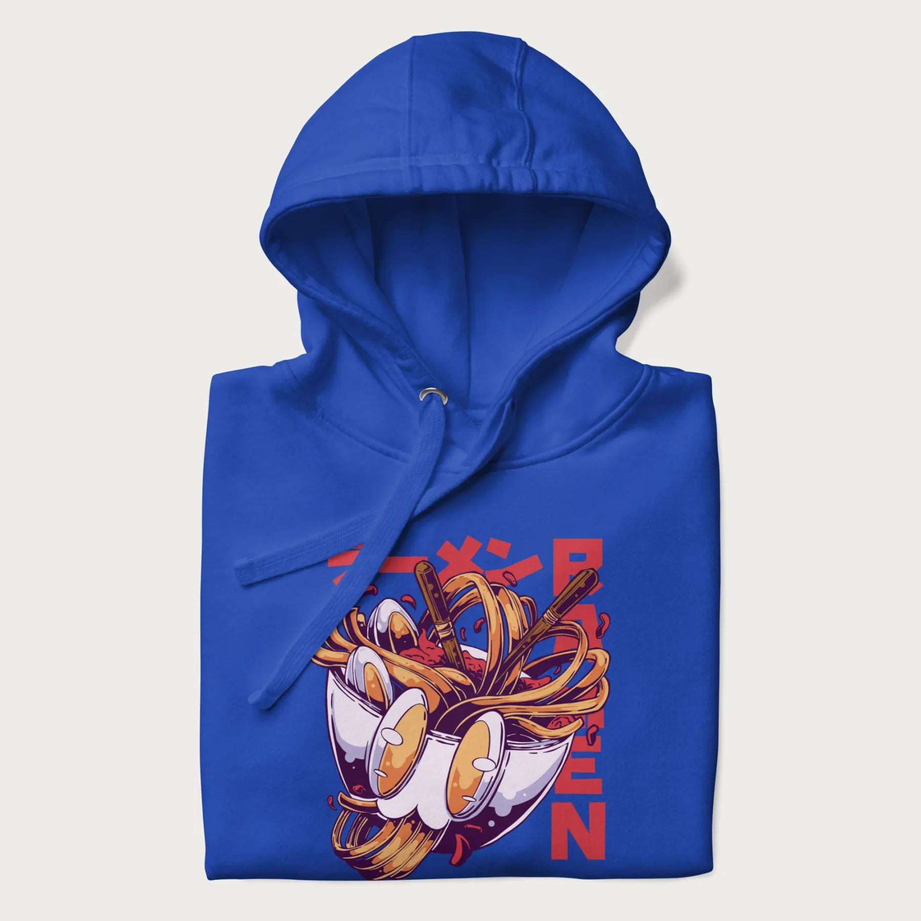 Folded royal blue hoodie with Japanese graphic of a ramen bowl with noodles, eggs and Japanese text 'ラーメン' (Ramen) in bold red text.
