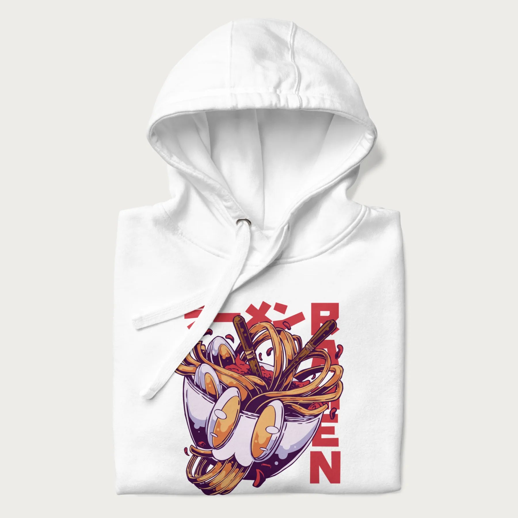 Folded white hoodie with Japanese graphic of a ramen bowl with noodles, eggs and Japanese text 'ラーメン' (Ramen) in bold red text.