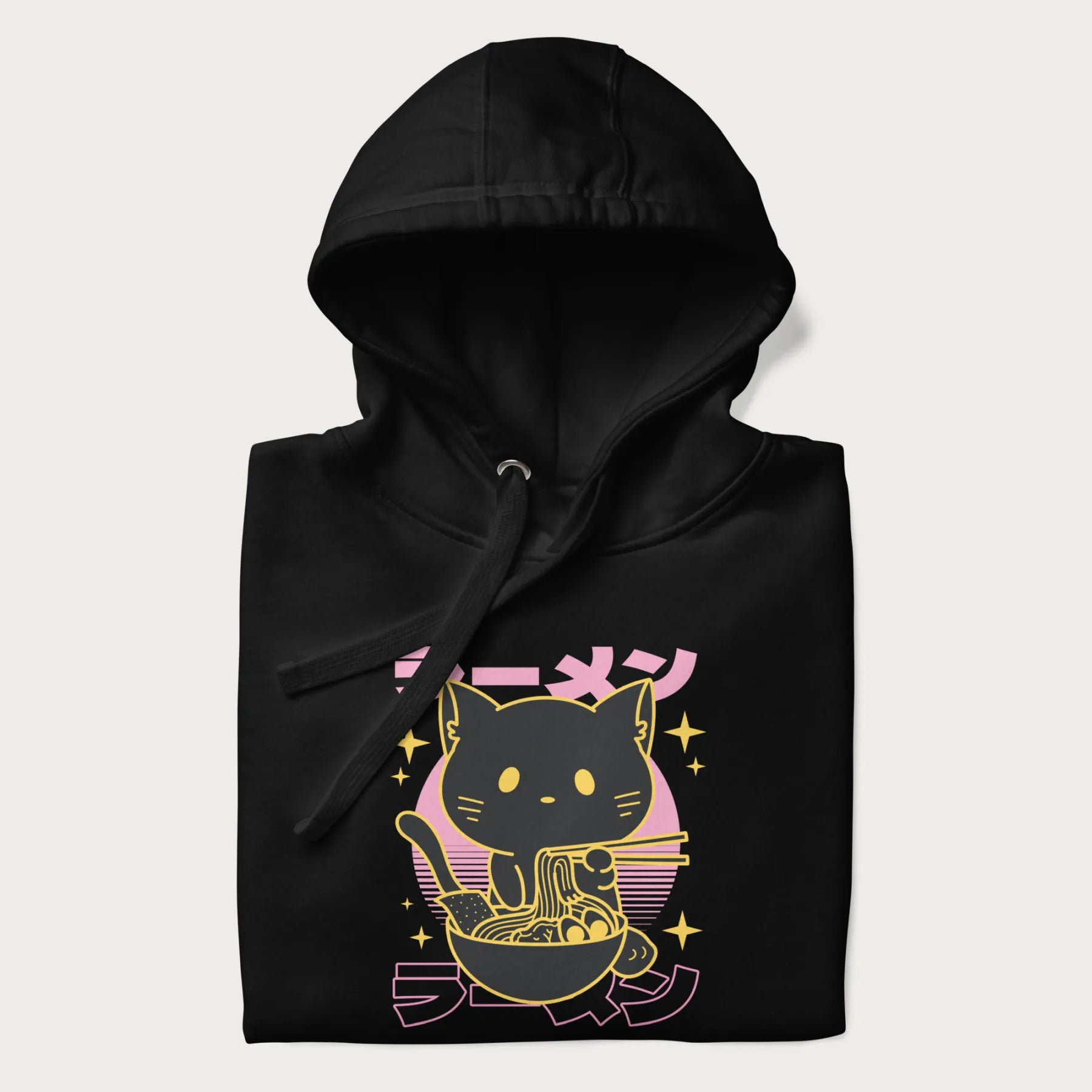 Folded black hoodie with Japanese text 'ラーメン' (ramen) and a retro design of a cute black cat eating ramen.