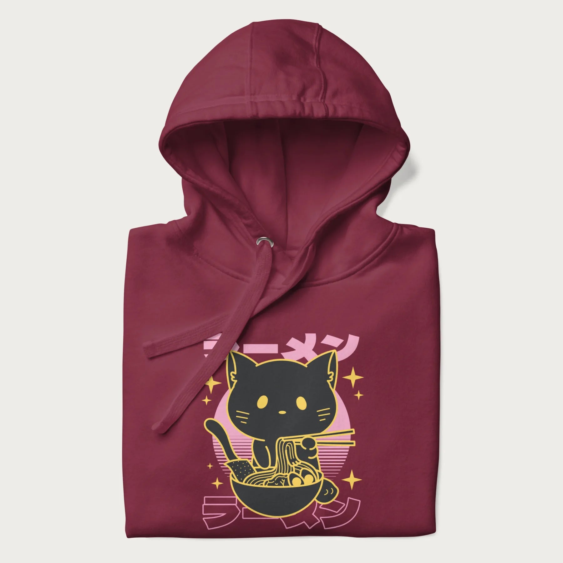 Folded maroon hoodie with Japanese text 'ラーメン' (ramen) and a retro design of a cute black cat eating ramen.