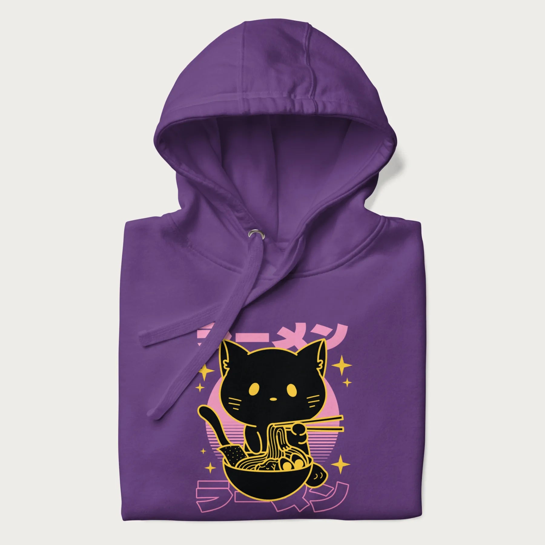 Folded purple hoodie with Japanese text 'ラーメン' (ramen) and a retro design of a cute black cat eating ramen.