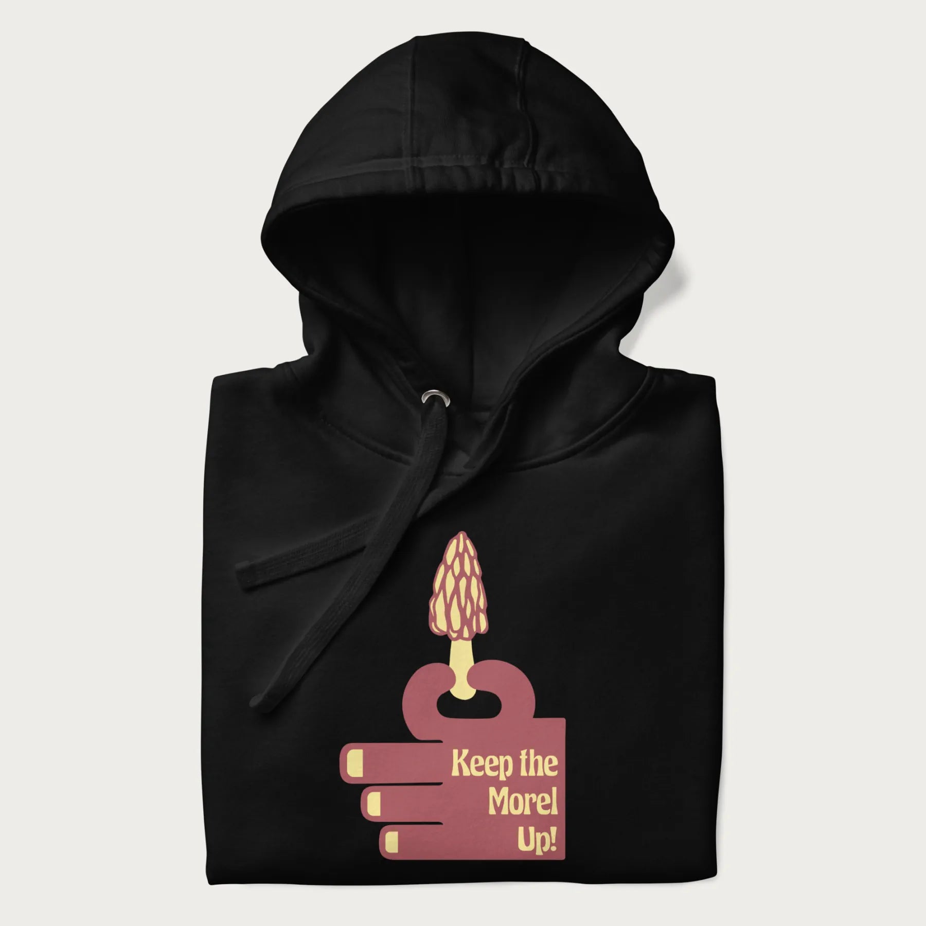 Folded black hoodie with a simple graphic of a hand holding a morel mushroom and the phrase 'Keep the Morel Up!'