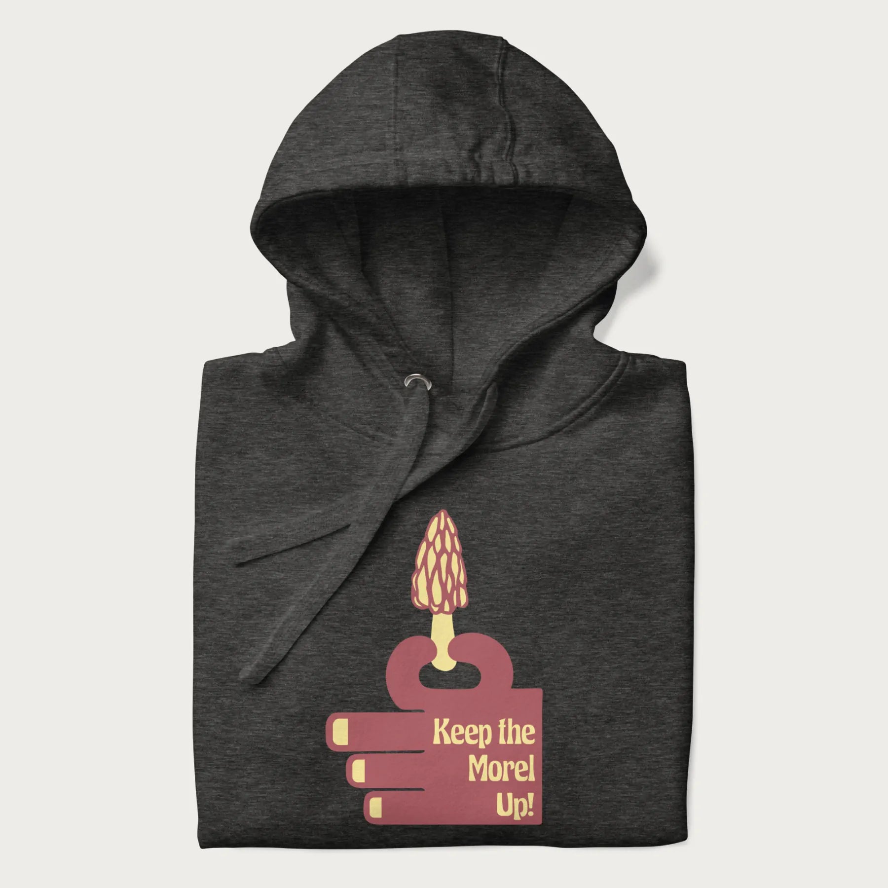 Folded dark grey hoodie with a simple graphic of a hand holding a morel mushroom and the phrase 'Keep the Morel Up!'