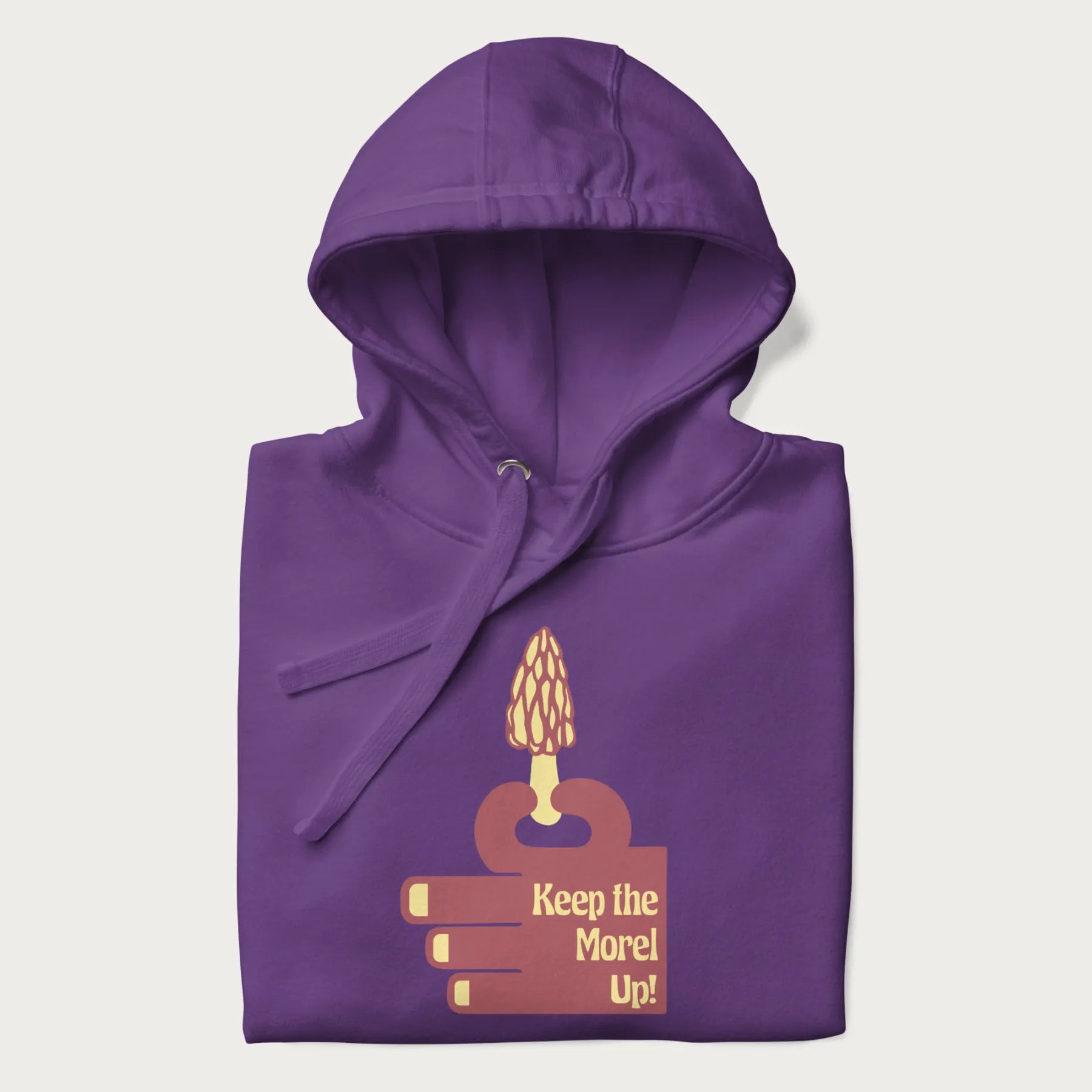 Folded purple hoodie with a simple graphic of a hand holding a morel mushroom and the phrase 'Keep the Morel Up!'