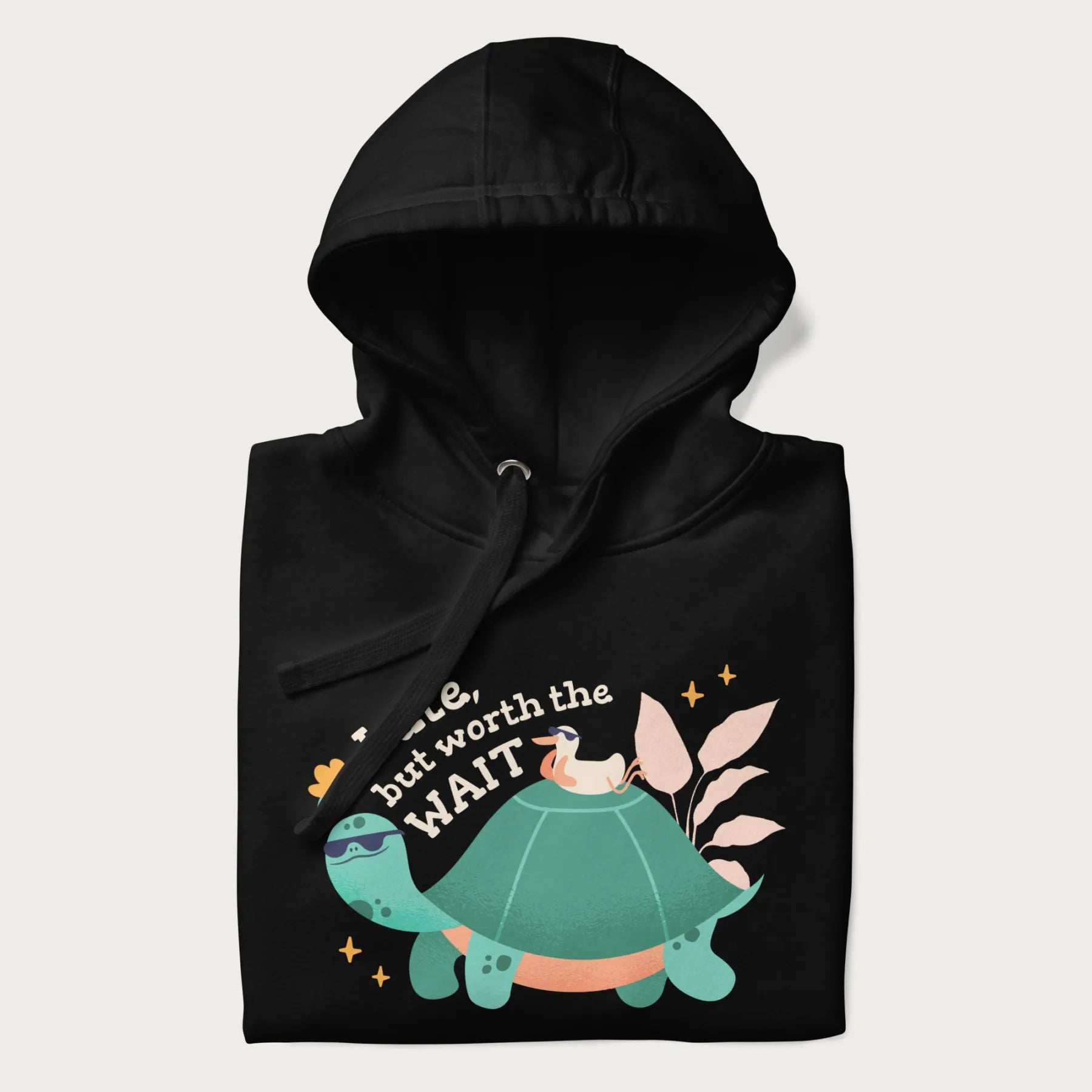 Folded black hoodie with graphic of a turtle and duck with sunglasses and the text 'Late but Worth the Wait'.