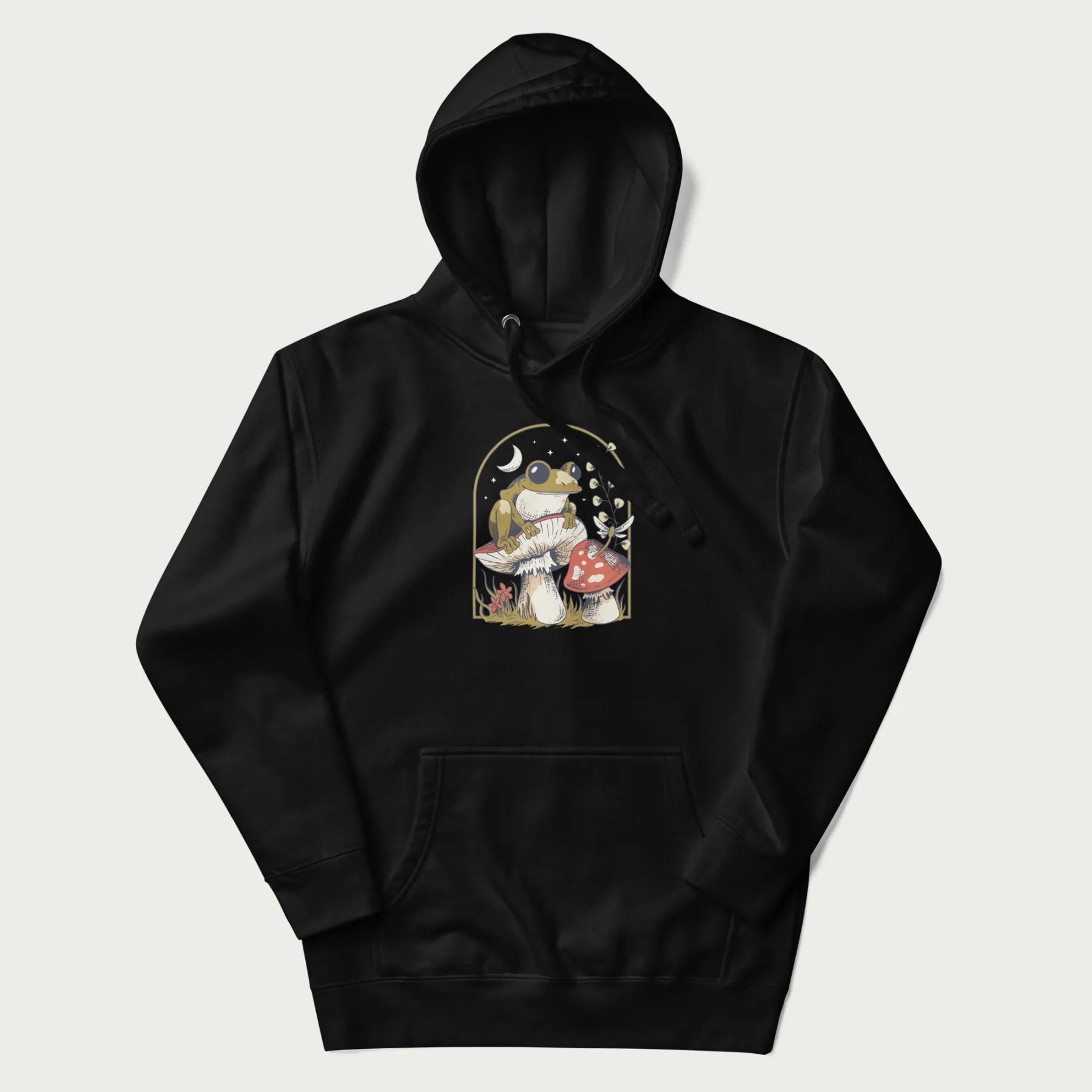 Black hoodie with cottagecore graphic of a frog perched on a mushroom, surrounded by additional mushrooms, flowers, and a crescent moon with stars.