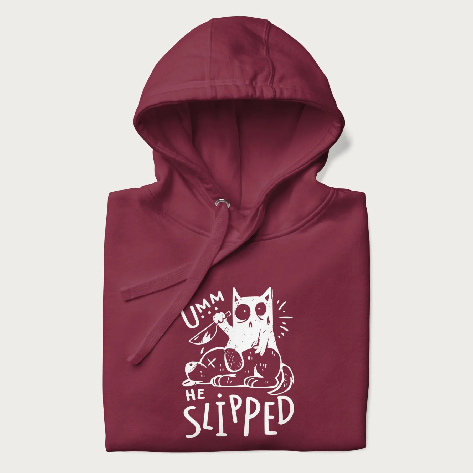 Folded maroon hoodie with a graphic of a white cat holding a knife over a dog with a funny phrase 'Umm, He Slipped'.