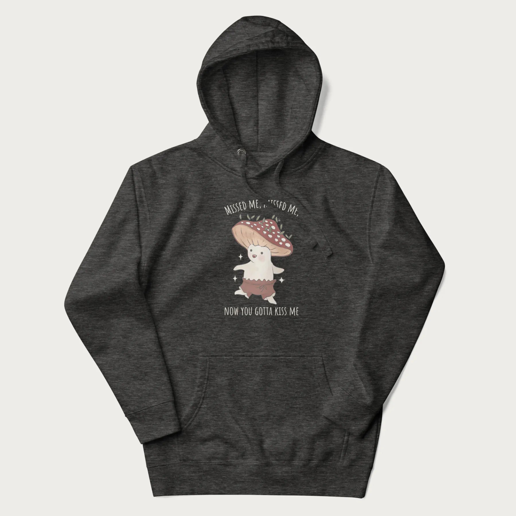 Dark grey hoodie with a graphic of a cute cottagecore mushroom character dancing and the phrase 'Missed Me, Missed Me, Now You Gotta Kiss Me'.