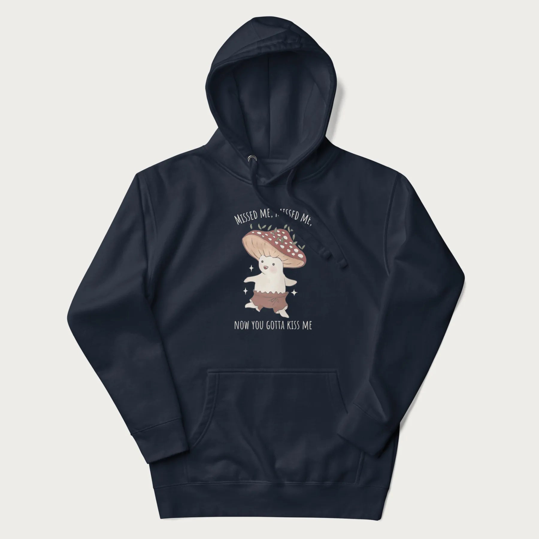 Navy blue hoodie with a graphic of a cute cottagecore mushroom character dancing and the phrase 'Missed Me, Missed Me, Now You Gotta Kiss Me'.