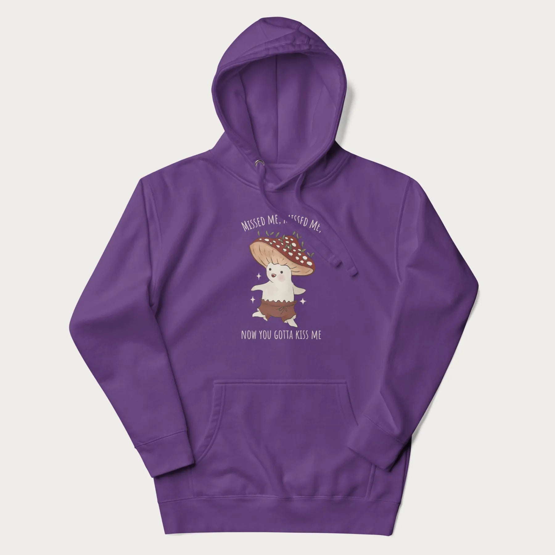 Purple hoodie with a graphic of a cute cottagecore mushroom character dancing and the phrase 'Missed Me, Missed Me, Now You Gotta Kiss Me'.
