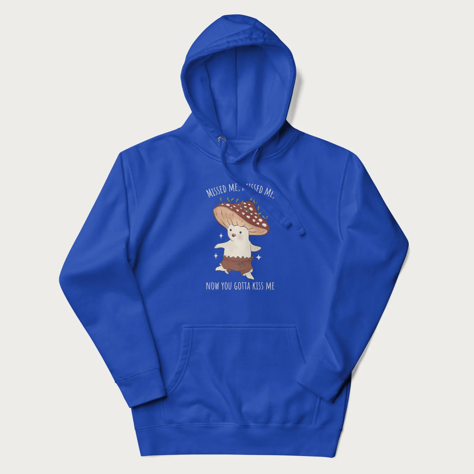 Royal blue hoodie with a graphic of a cute cottagecore mushroom character dancing and the phrase 'Missed Me, Missed Me, Now You Gotta Kiss Me'.
