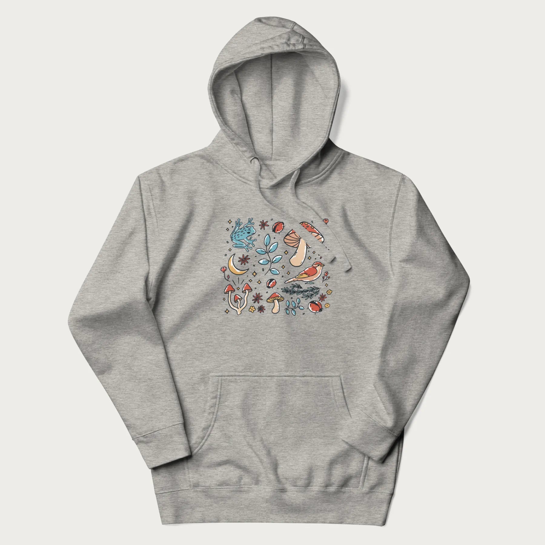 Light grey hoodie with a graphic of a blue frog, mushrooms, a bird, ladybugs, flowers, leaves, and a crescent moon.