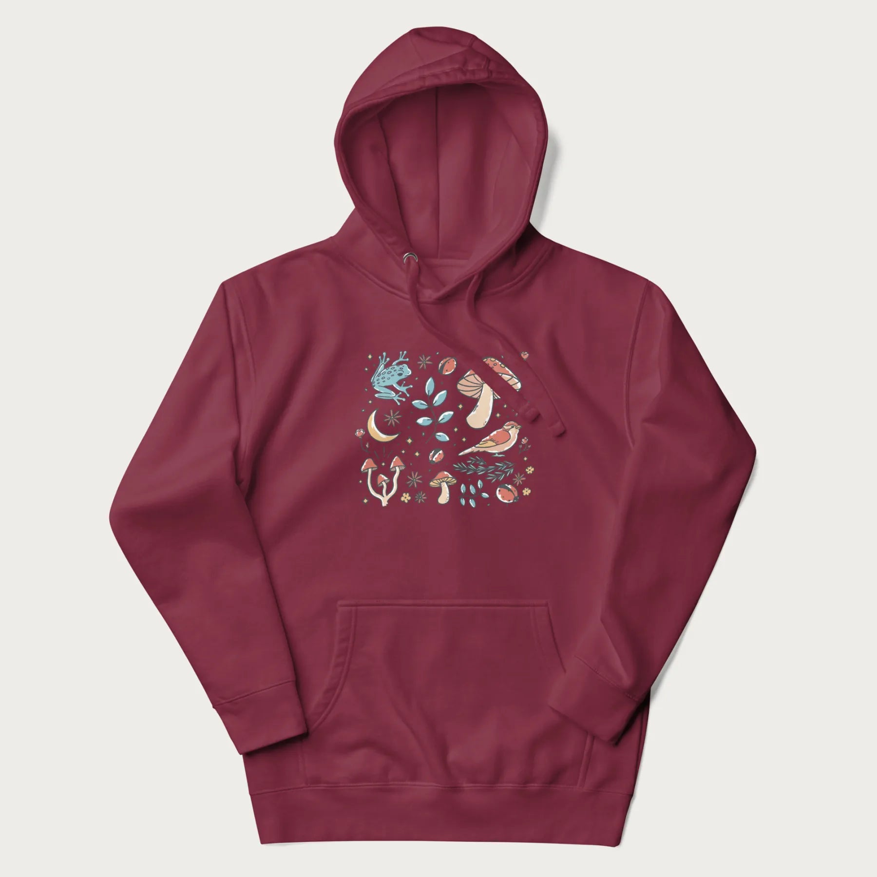 Maroon hoodie with a graphic of a blue frog, mushrooms, a bird, ladybugs, flowers, leaves, and a crescent moon.