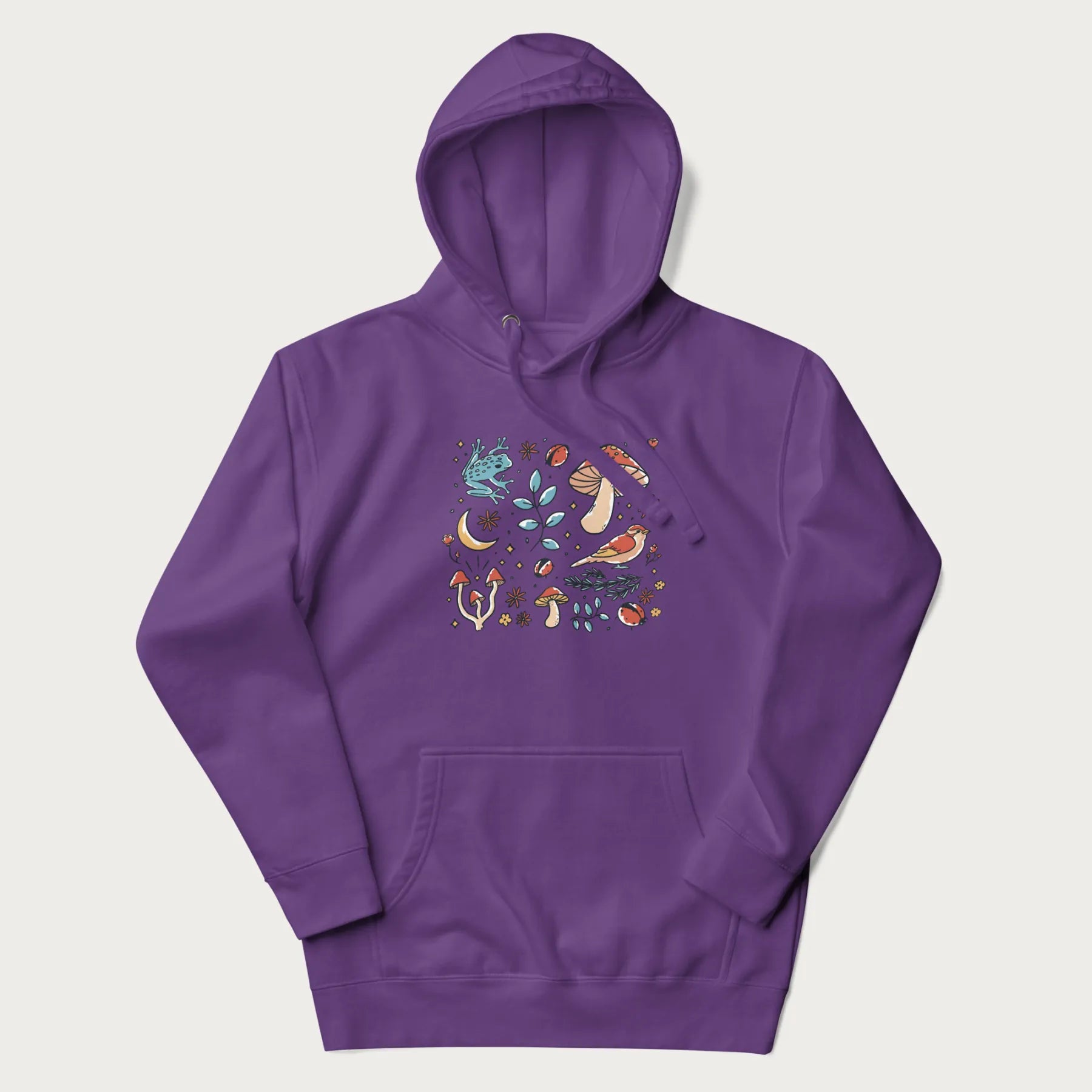 Purple hoodie with a graphic of a blue frog, mushrooms, a bird, ladybugs, flowers, leaves, and a crescent moon.