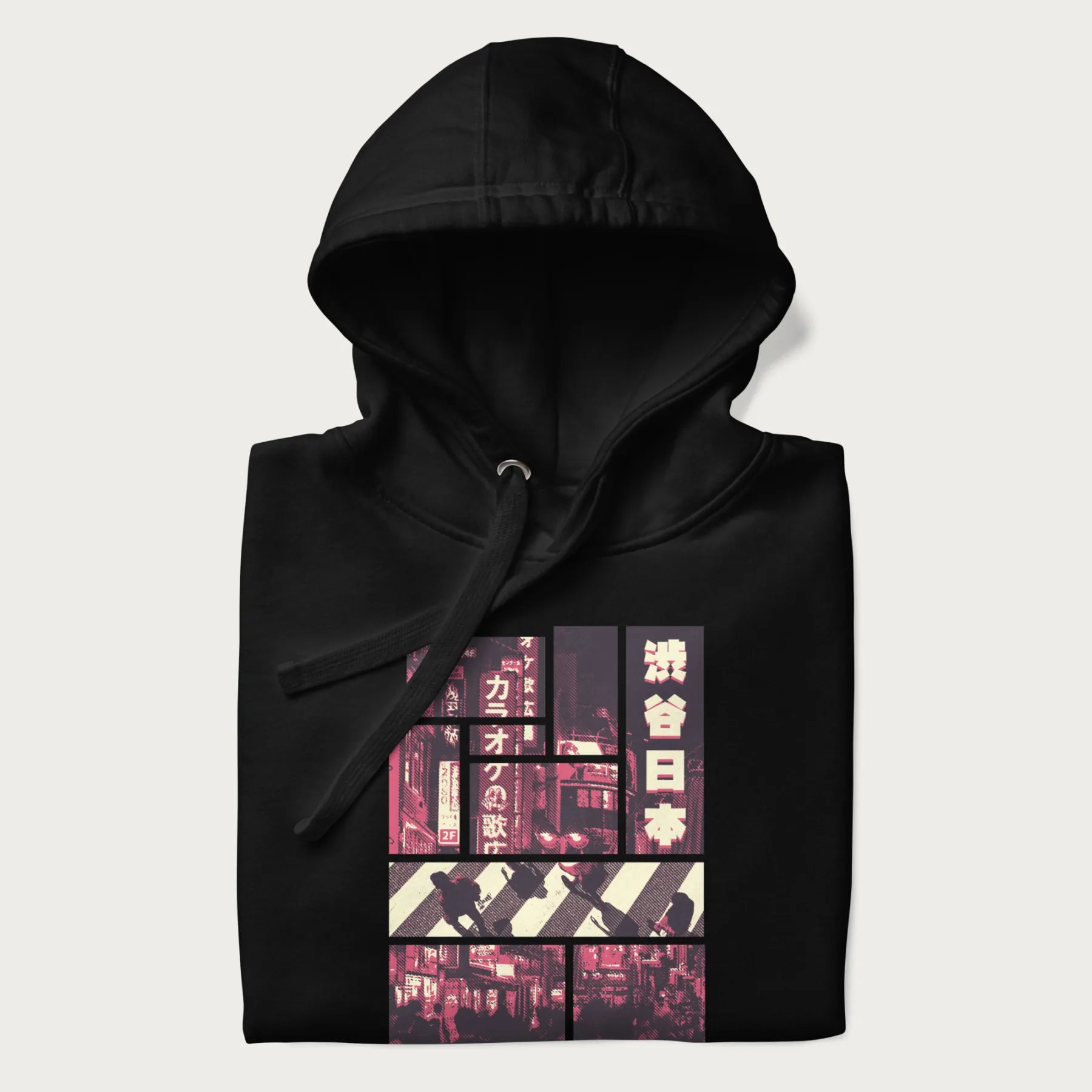 Folded black hoodie with Japanese graphic panels of Shibuya Crossing, Japanese text, and neon signs.