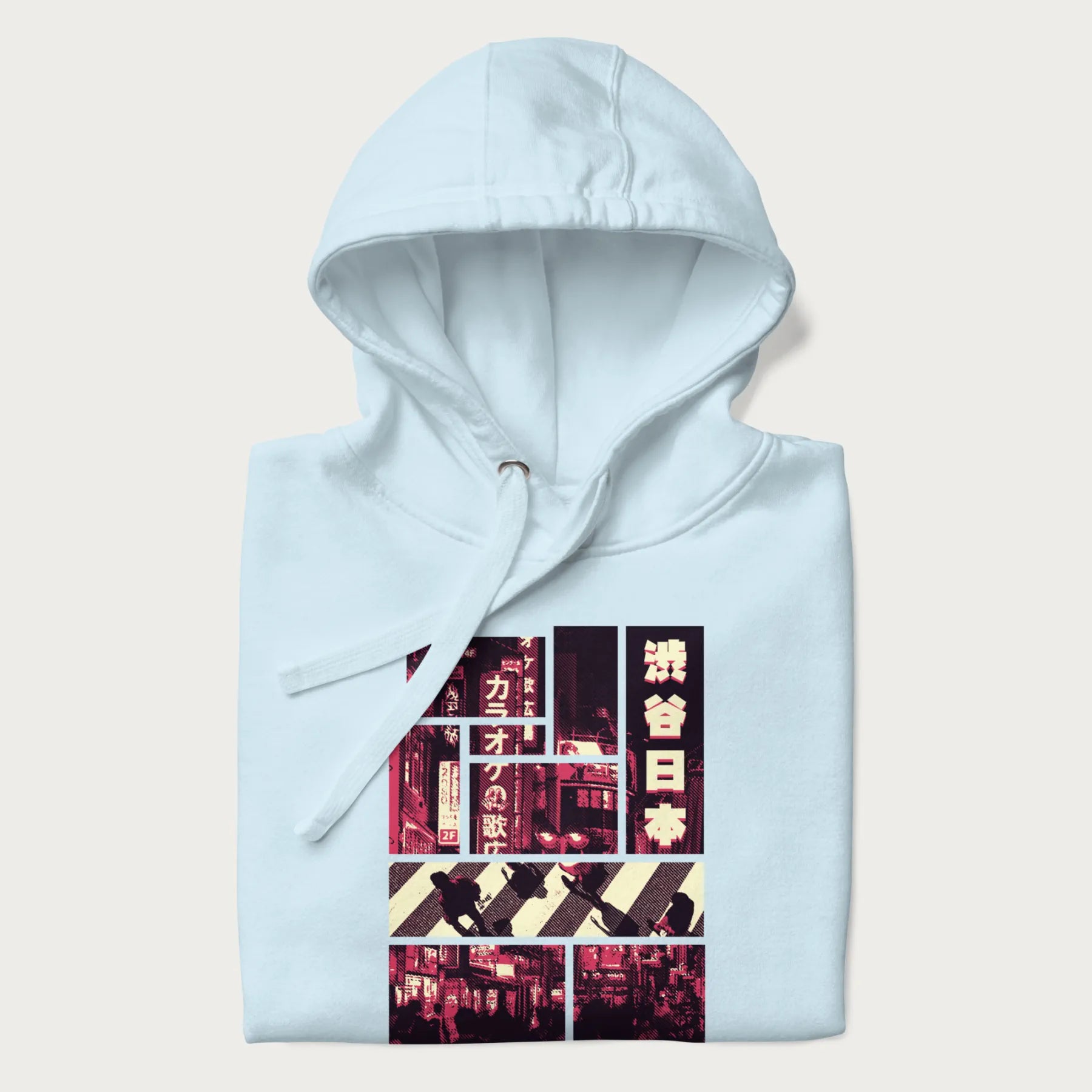 Folded light blue hoodie with Japanese graphic panels of Shibuya Crossing, Japanese text, and neon signs.