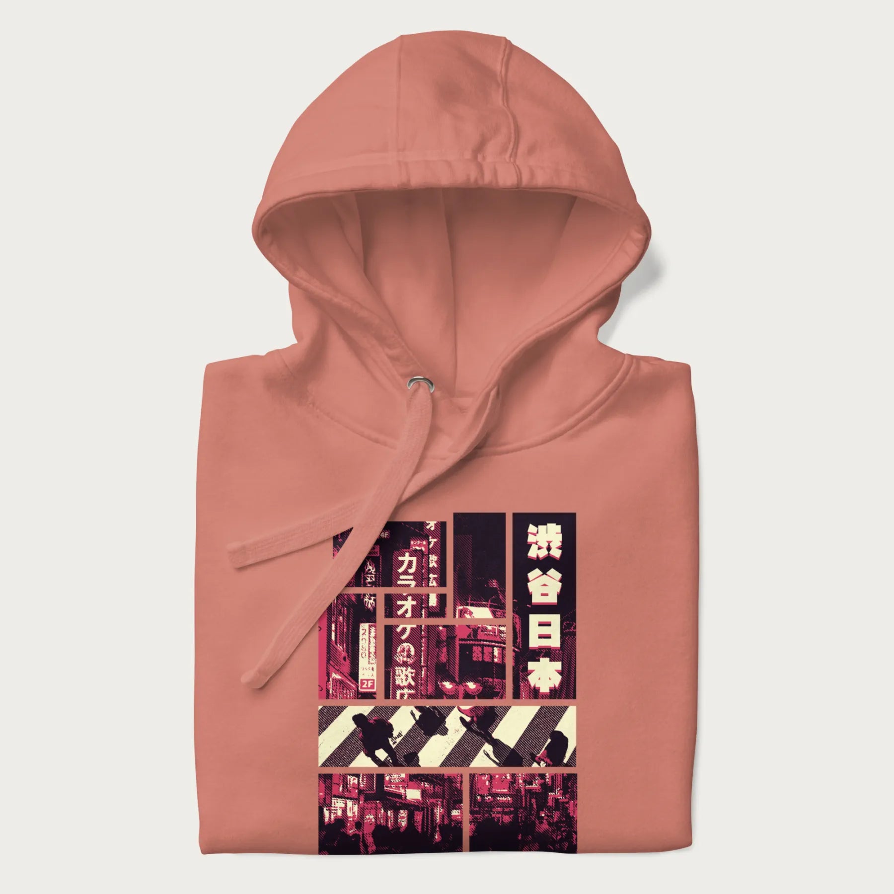 Folded light pink hoodie with Japanese graphic panels of Shibuya Crossing, Japanese text, and neon signs.