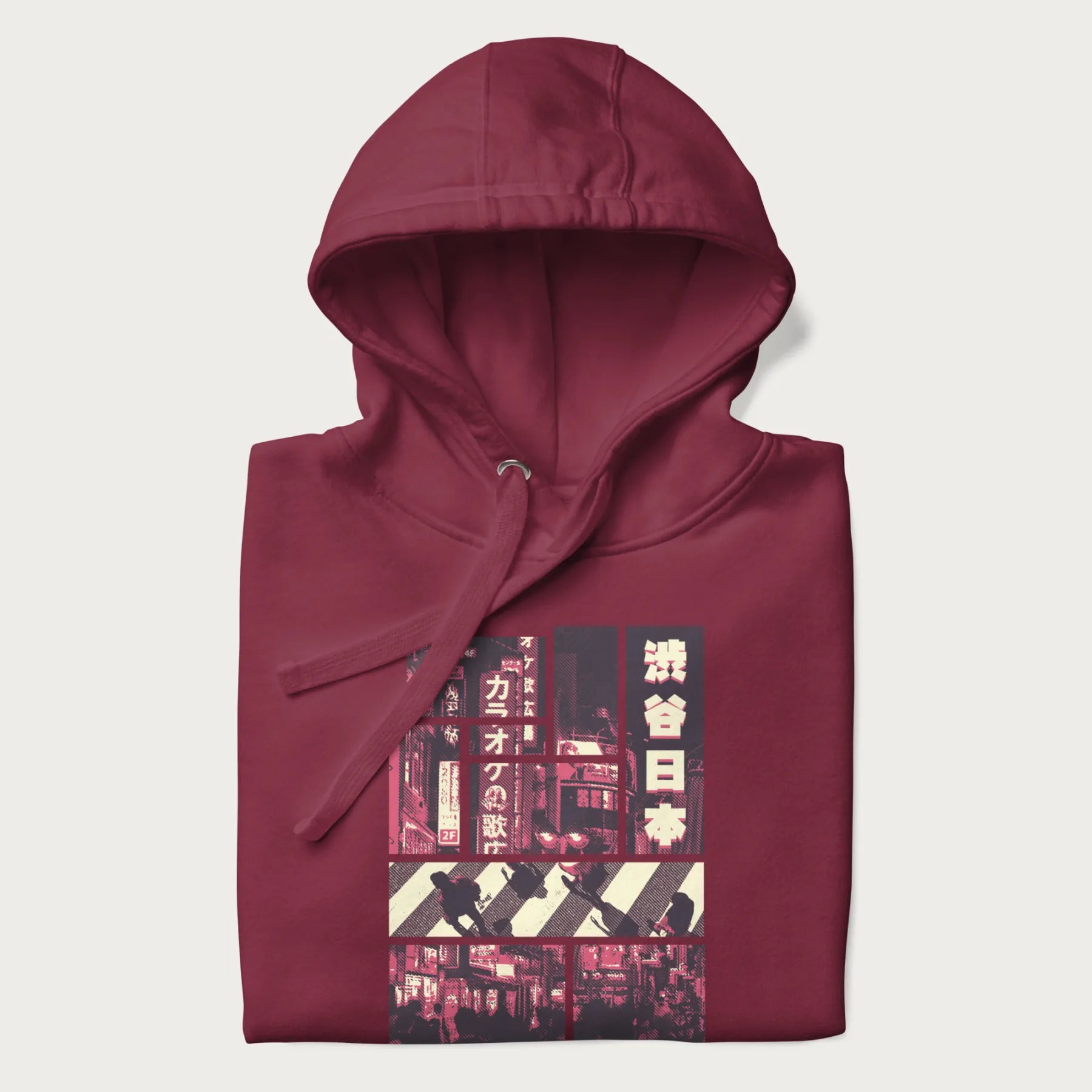 Folded maroon hoodie with Japanese graphic panels of Shibuya Crossing, Japanese text, and neon signs.