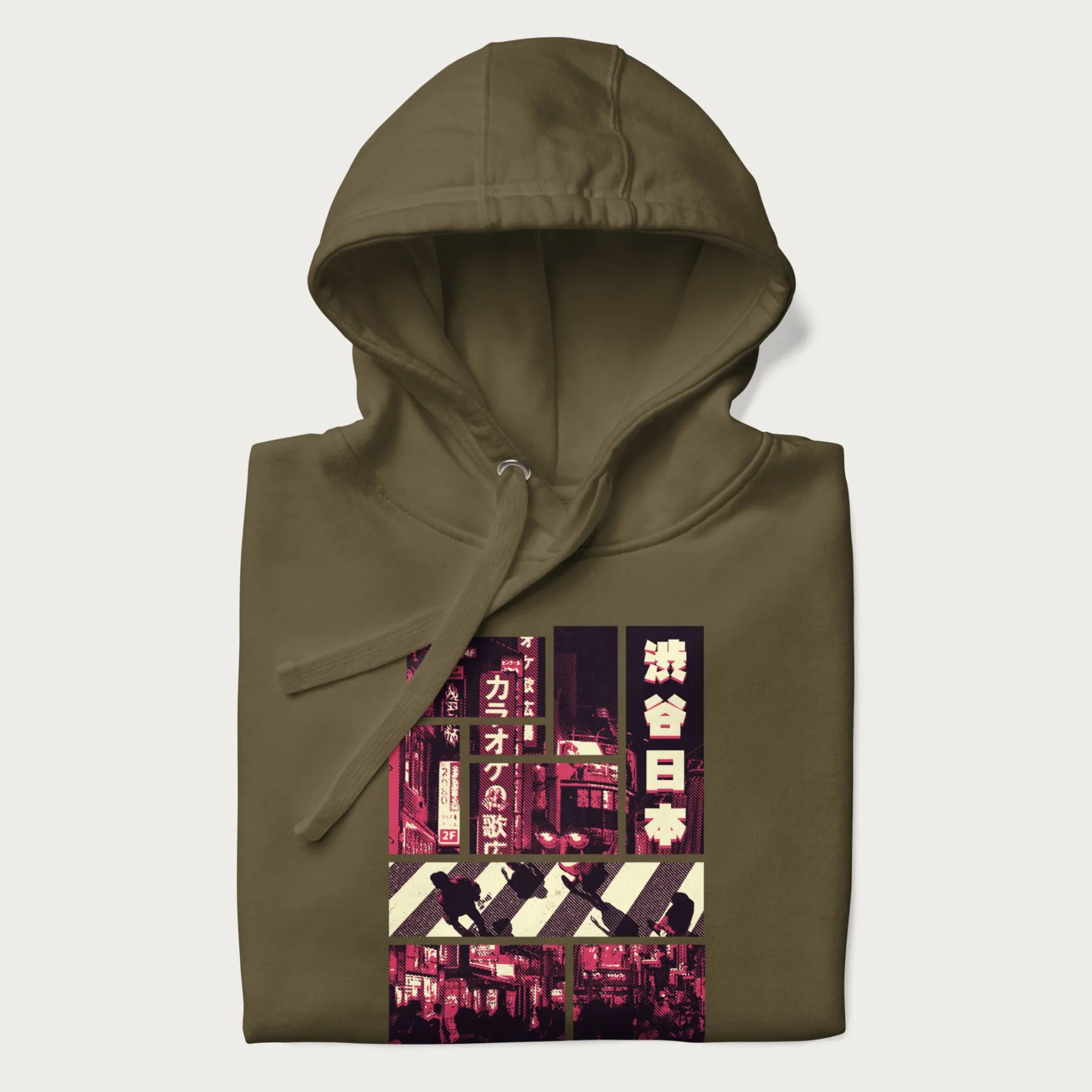 Folded military green hoodie with Japanese graphic panels of Shibuya Crossing, Japanese text, and neon signs.