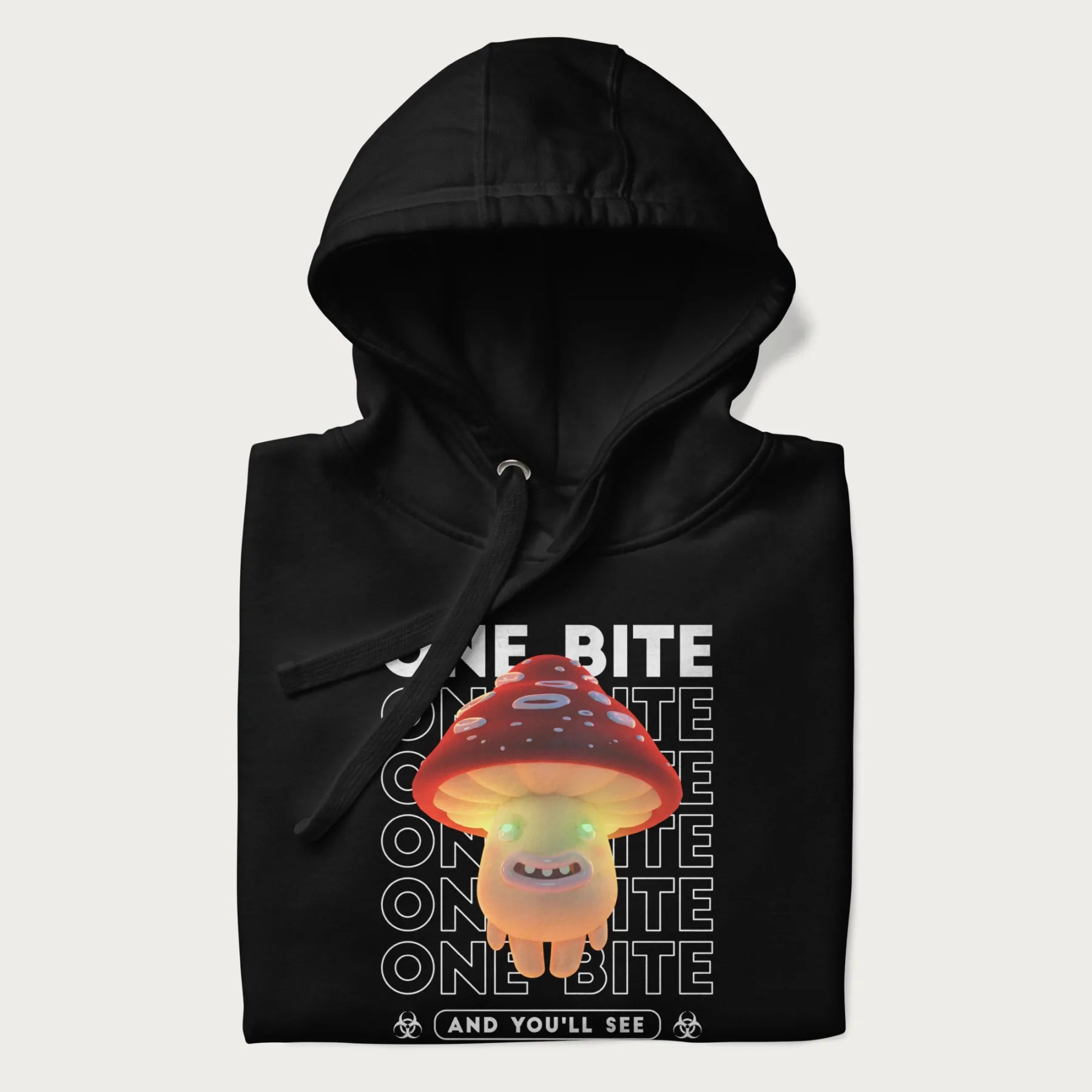 Folded black hoodie with a graphic of a glowing, cartoon realistic mushroom character and the text 'One Bite And You'll See'.