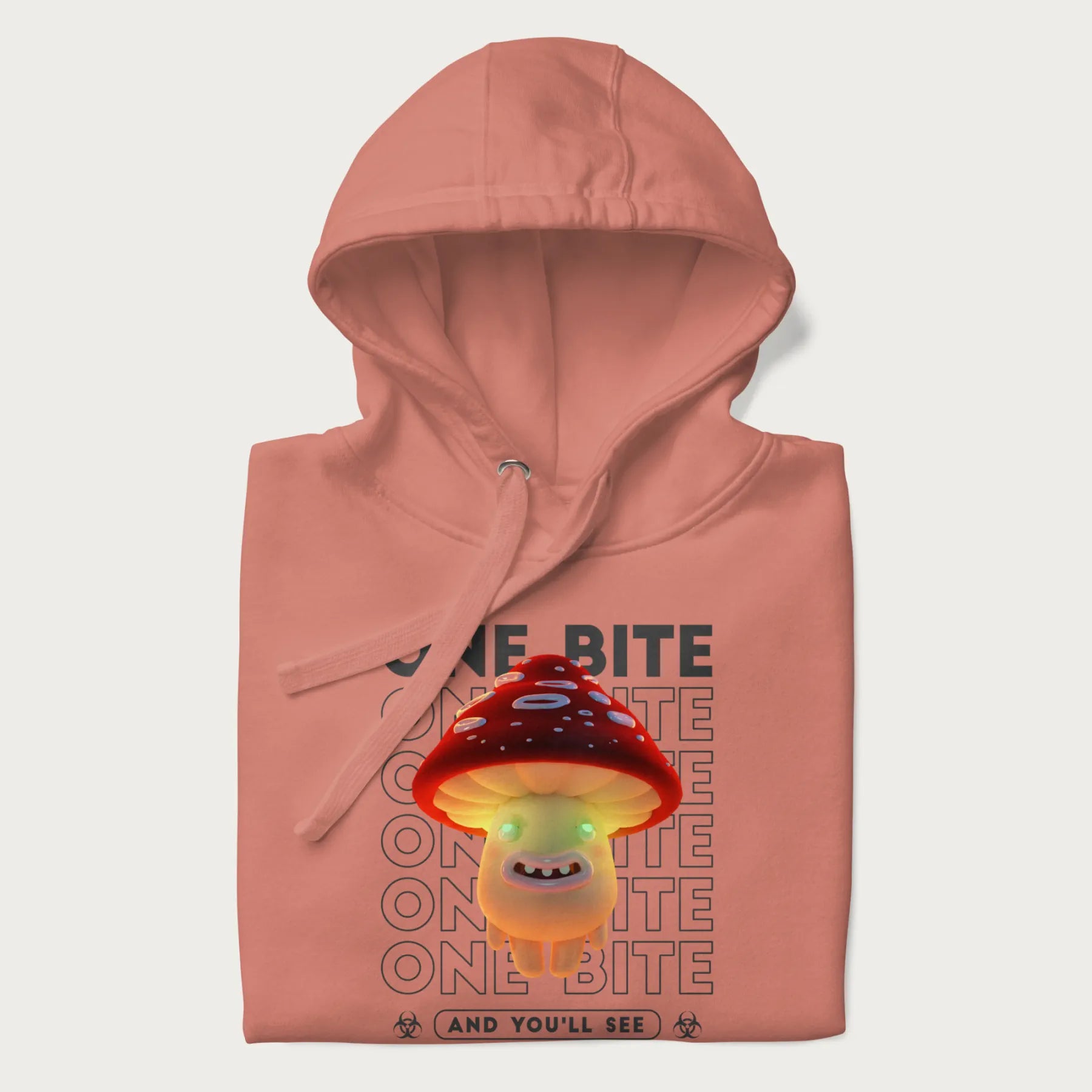 Folded light pink hoodie with a graphic of a glowing, cartoon realistic mushroom character and the text 'One Bite And You'll See'.