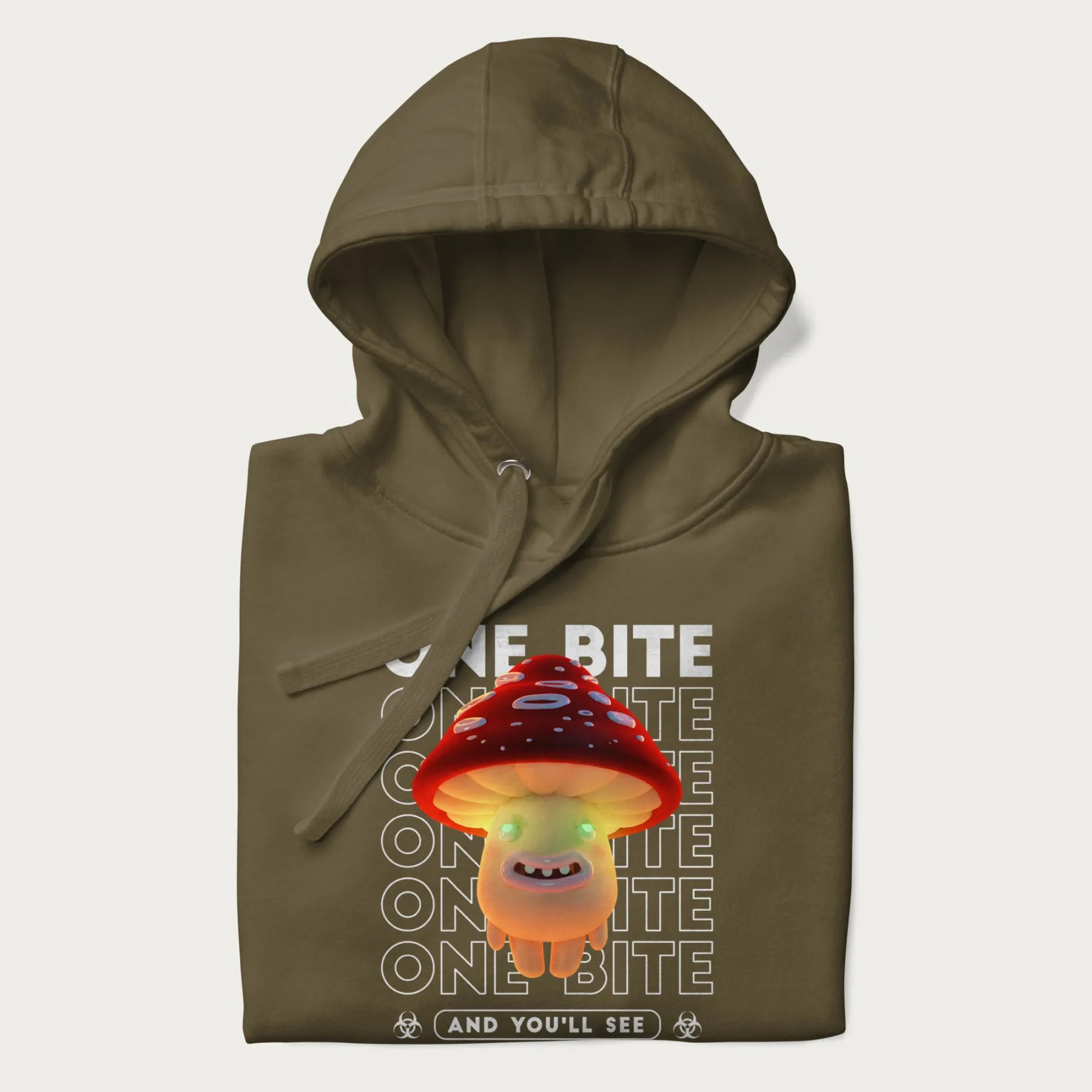 Folded military green hoodie with a graphic of a glowing, cartoon realistic mushroom character and the text 'One Bite And You'll See'.