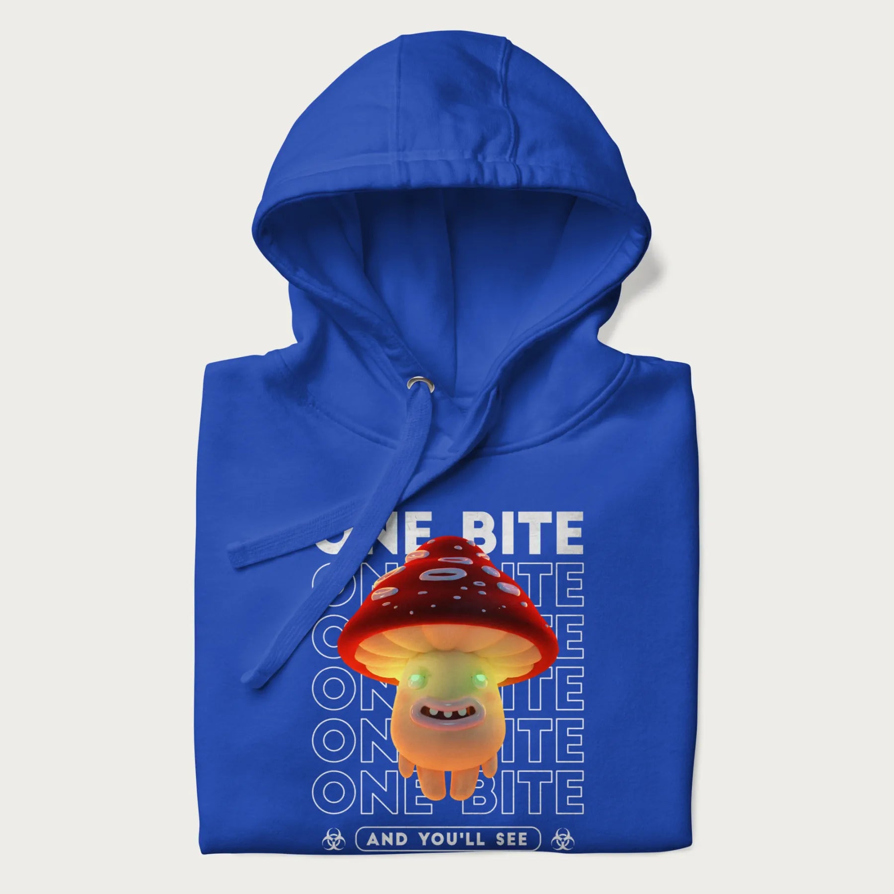 Folded royal blue hoodie with a graphic of a glowing, cartoon realistic mushroom character and the text 'One Bite And You'll See'.