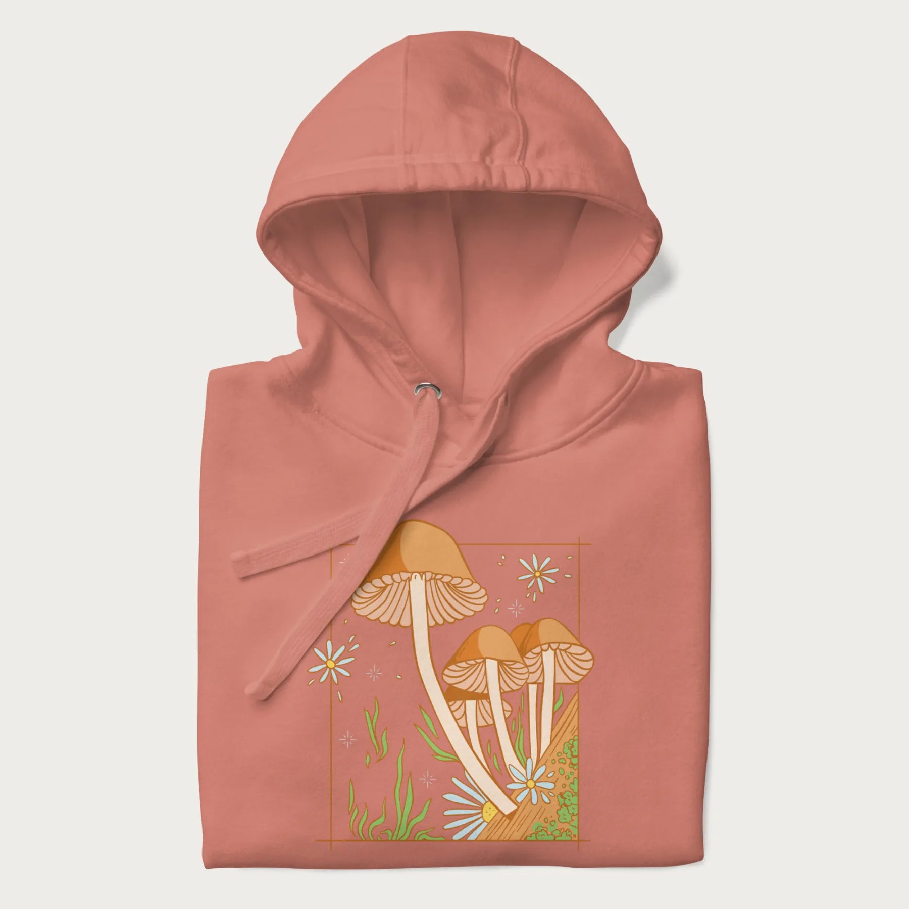 Folded light pink hoodie with a detailed cottagecore illustration of Psilocybe mushrooms and flowers.