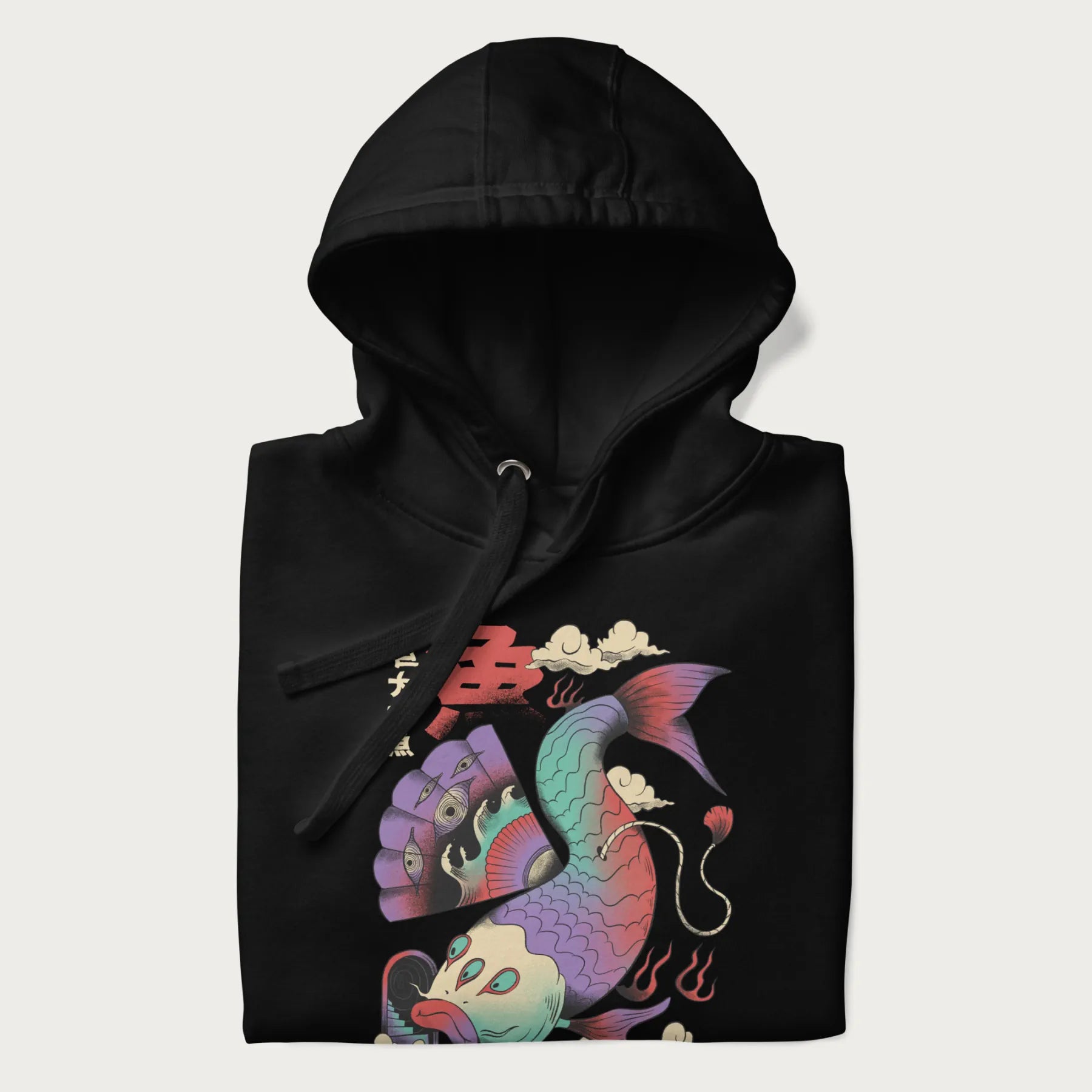 Folded black hoodie with Japanese graphic of a colorful psychedelic koi fish, with Japanese text '魚' (Fish) and '巨大な魚' (Giant Fish).