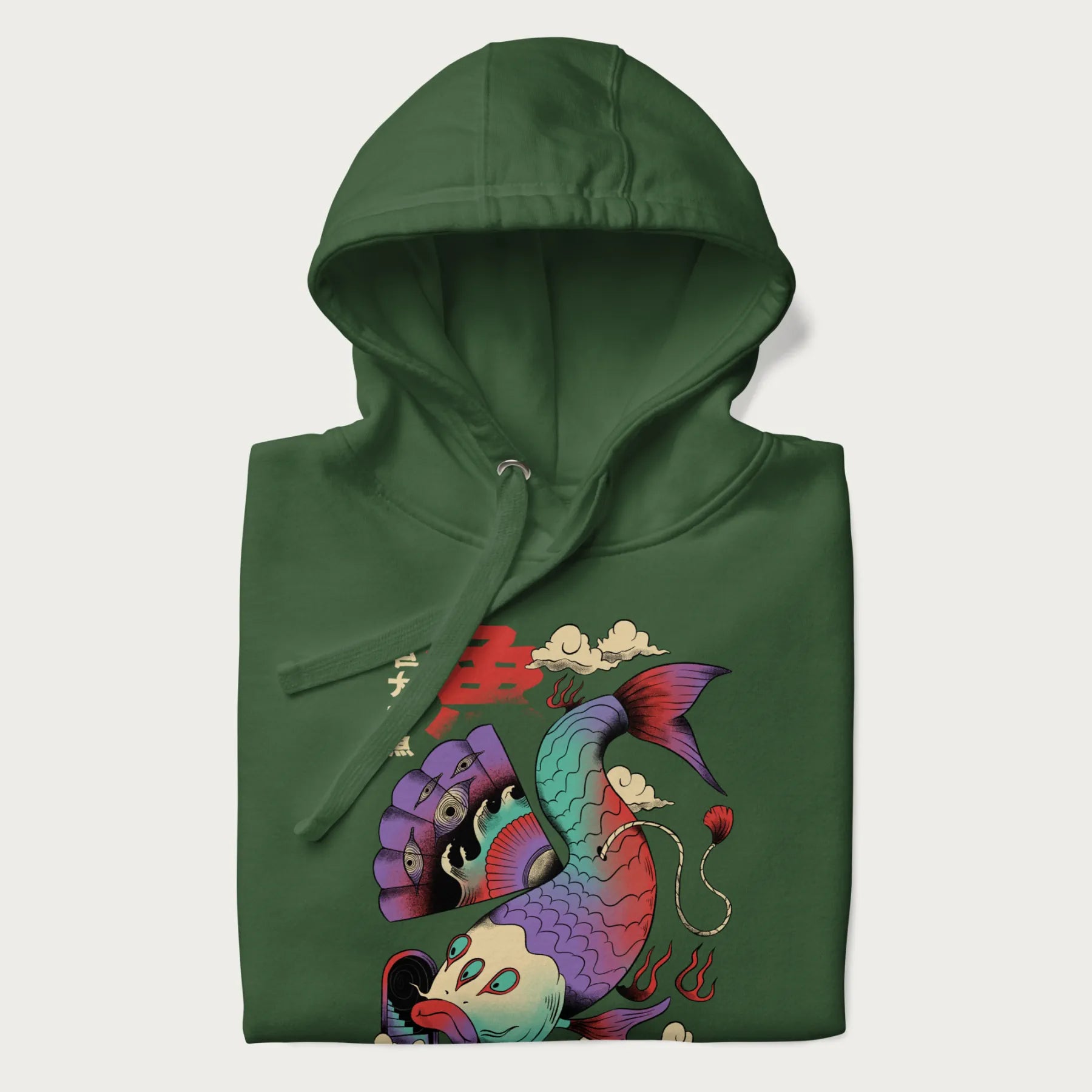 Folded forest green hoodie with Japanese graphic of a colorful psychedelic koi fish, with Japanese text '魚' (Fish) and '巨大な魚' (Giant Fish).