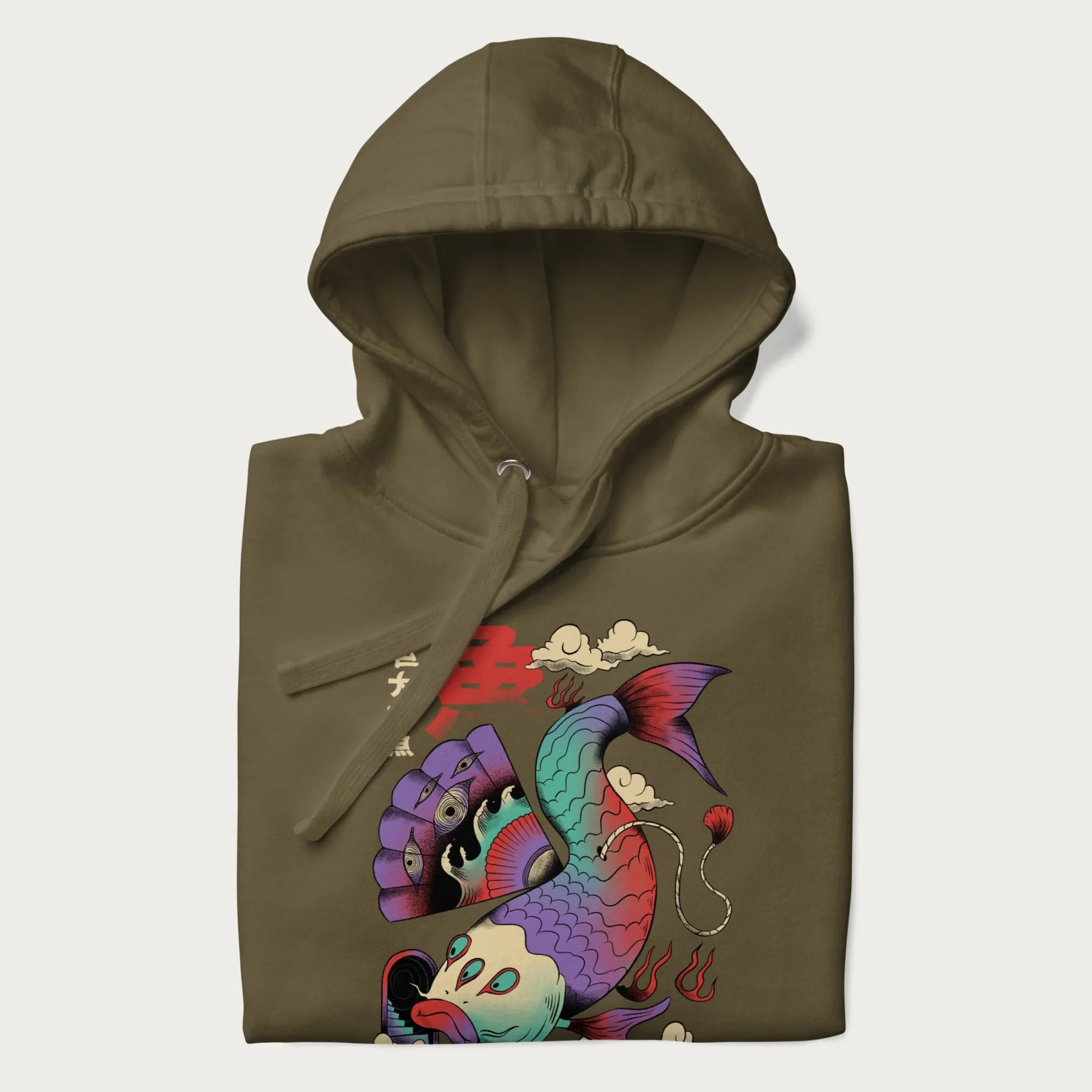 Folded military green hoodie with Japanese graphic of a colorful psychedelic koi fish, with Japanese text '魚' (Fish) and '巨大な魚' (Giant Fish).