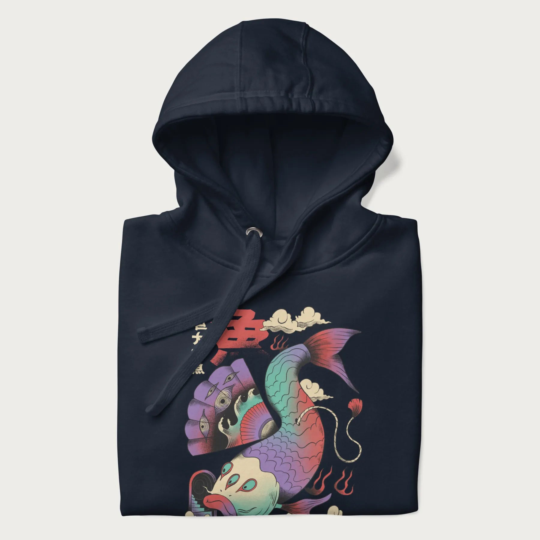 Folded navy blue hoodie with Japanese graphic of a colorful psychedelic koi fish, with Japanese text '魚' (Fish) and '巨大な魚' (Giant Fish).