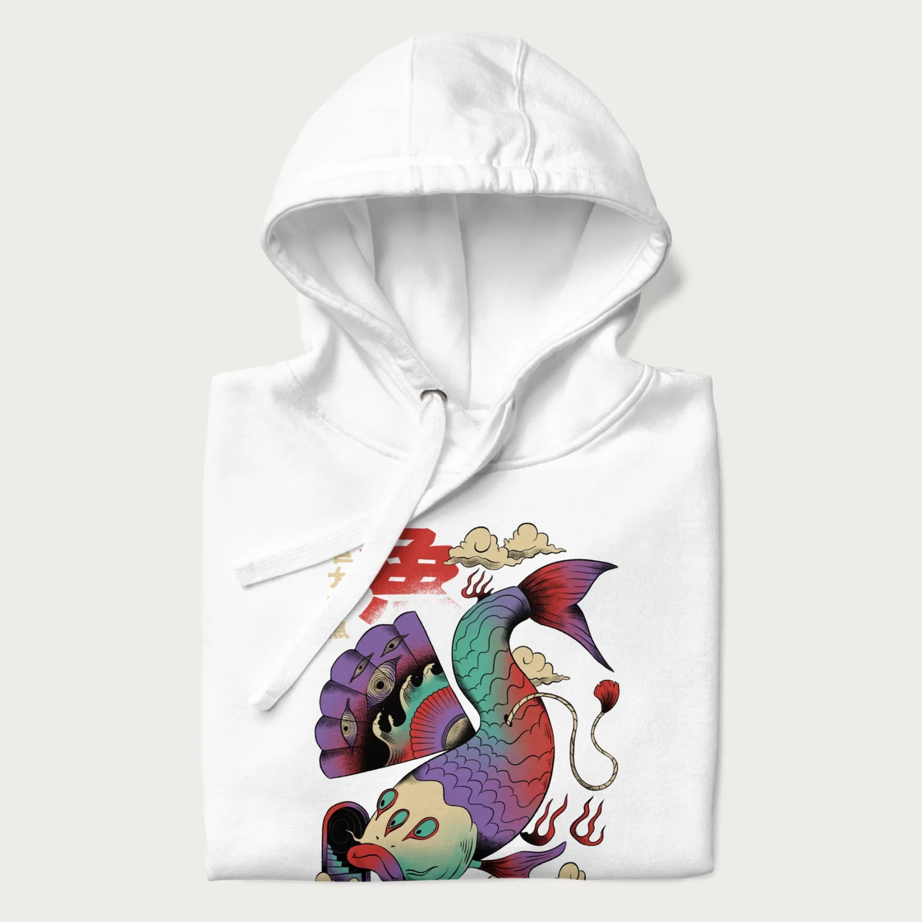 Folded white hoodie with Japanese graphic of a colorful psychedelic koi fish, with Japanese text '魚' (Fish) and '巨大な魚' (Giant Fish).
