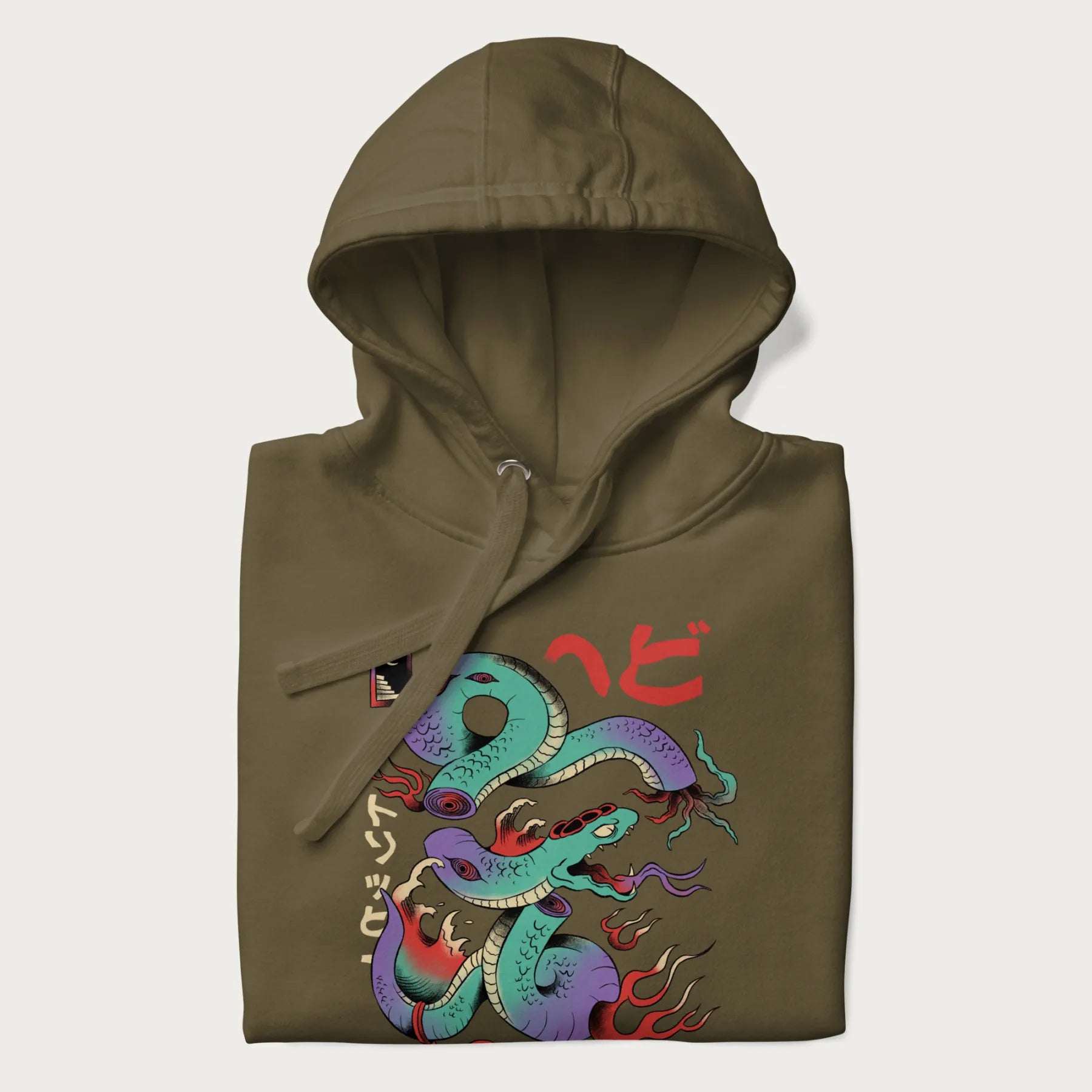 Folded military green hoodie with Japanese psychedelic snake graphic, with Japanese text 'ヘビ' (Snake) and 'トリッピー' (Trippy) in vibrant colors.