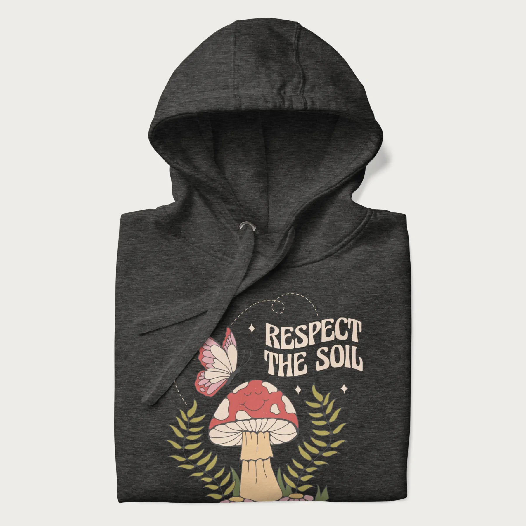 Folded dark grey hoodie with mushroom and butterfly design, with the text 'Respect the Soil' above it.