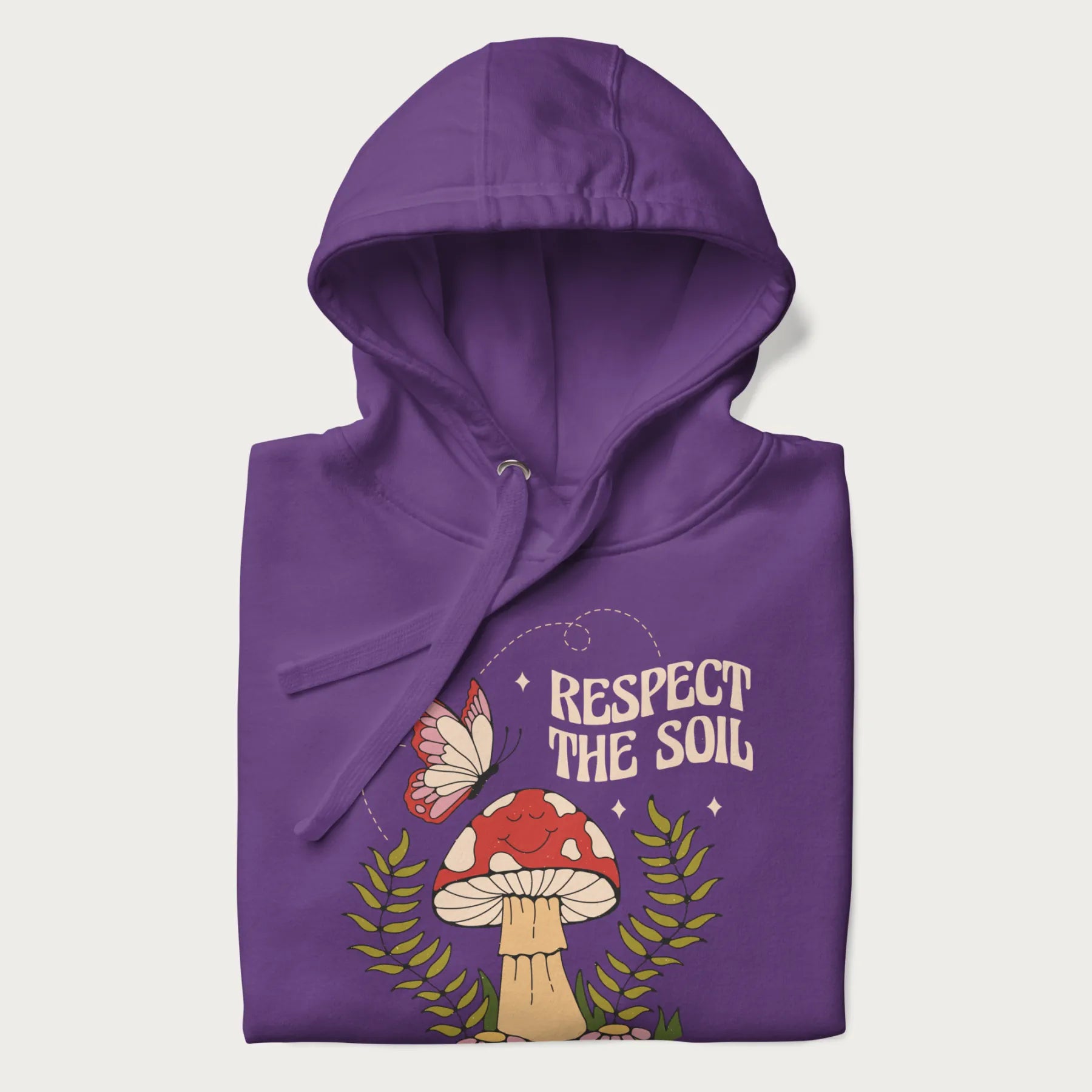Folded purple hoodie with mushroom and butterfly design, with the text 'Respect the Soil' above it.