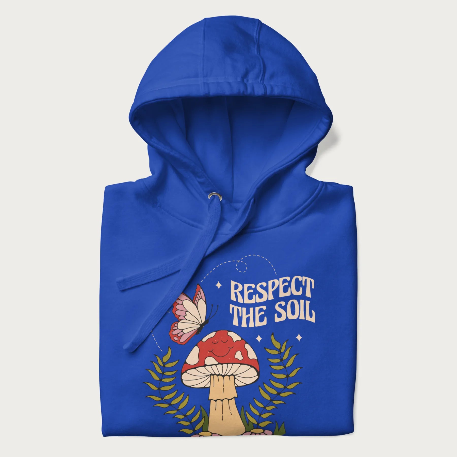 Folded royal blue hoodie with mushroom and butterfly design, with the text 'Respect the Soil' above it.