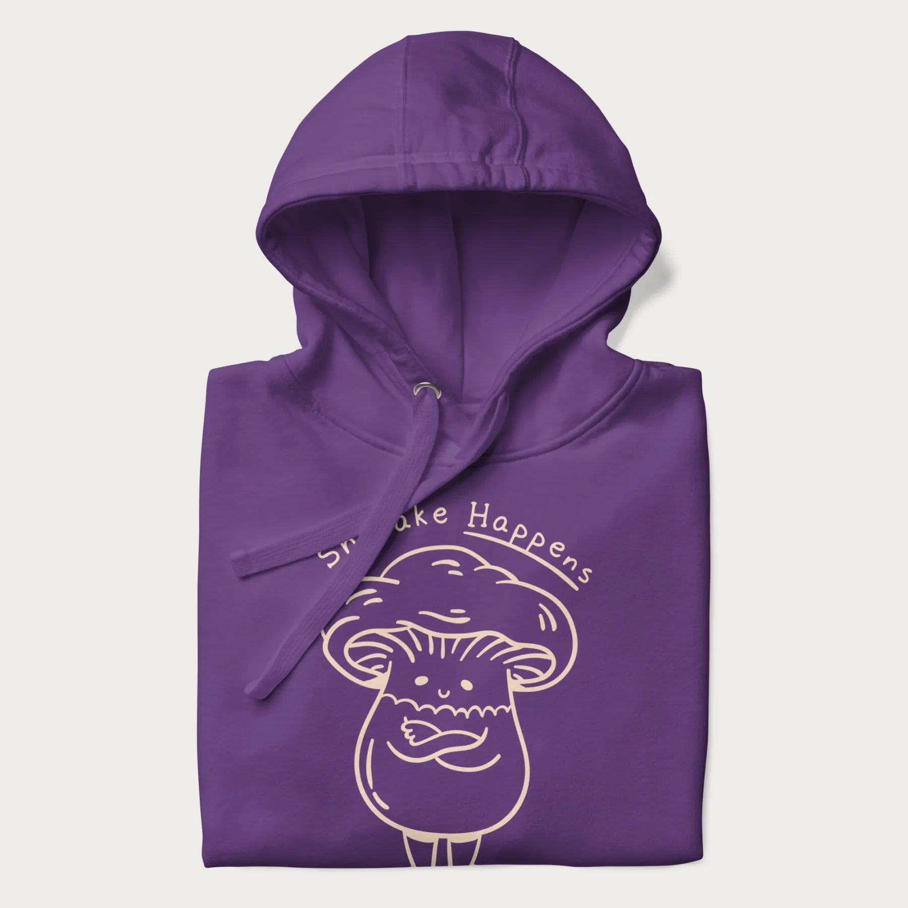 Folded purple hoodie featuring a cute shiitake mushroom graphic with the text "Shiitake Happens."