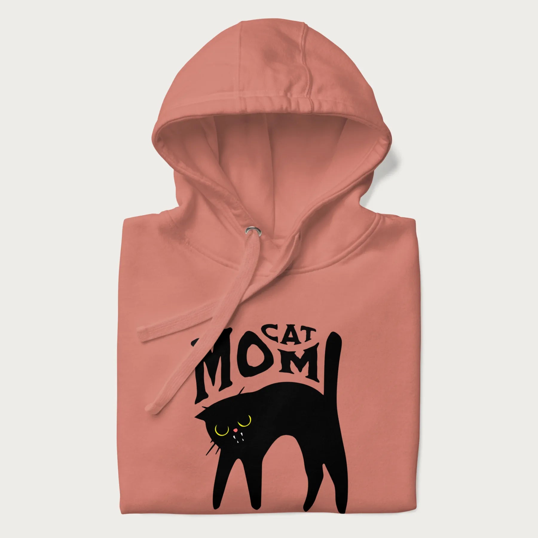 Folded light pink hoodie with 'Cat Mom' in black lettering above a minimalistic graphic of a black cat with yellow eyes.
