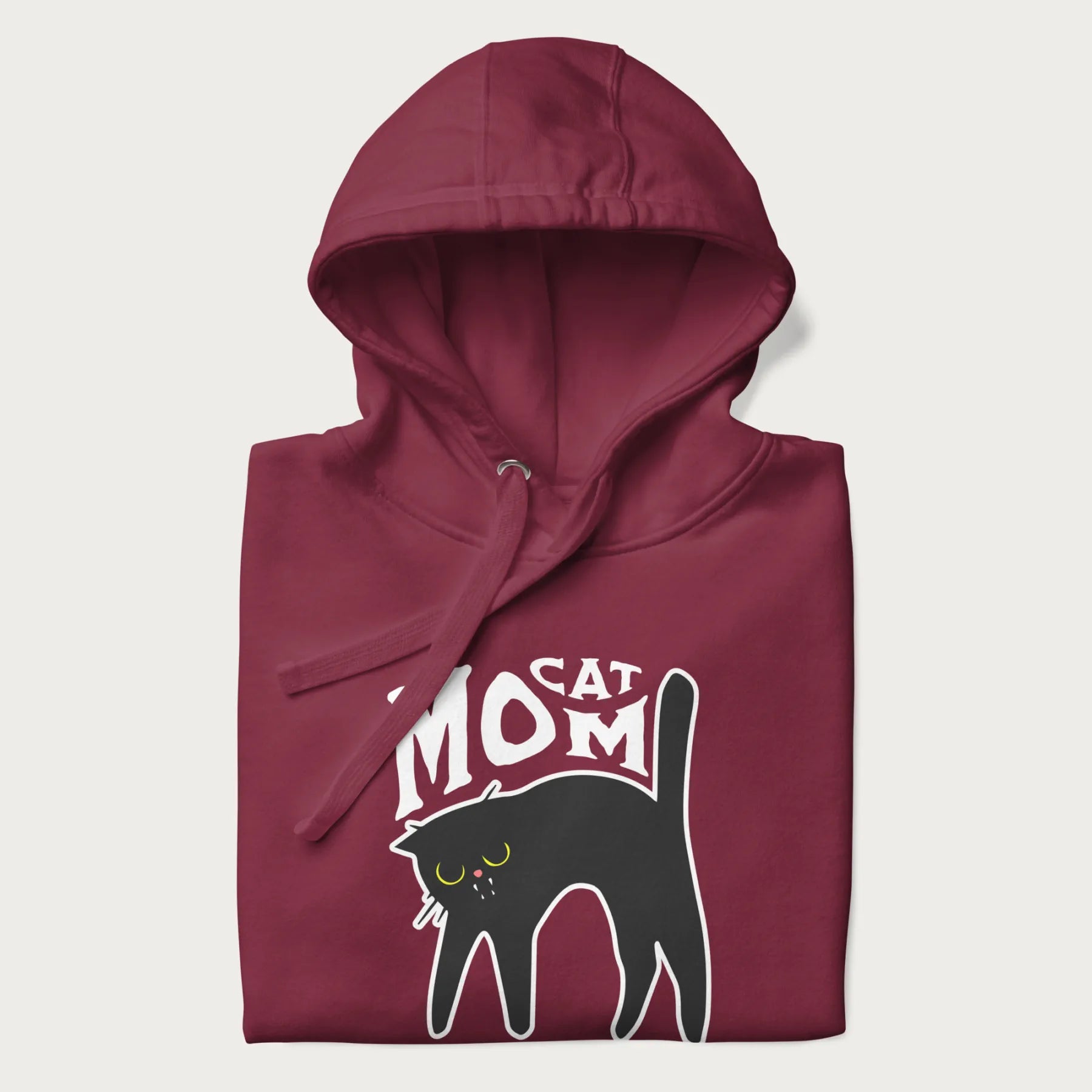 Folded maroon hoodie with 'Cat Mom' in white lettering above a minimalistic graphic of a black cat with yellow eyes.