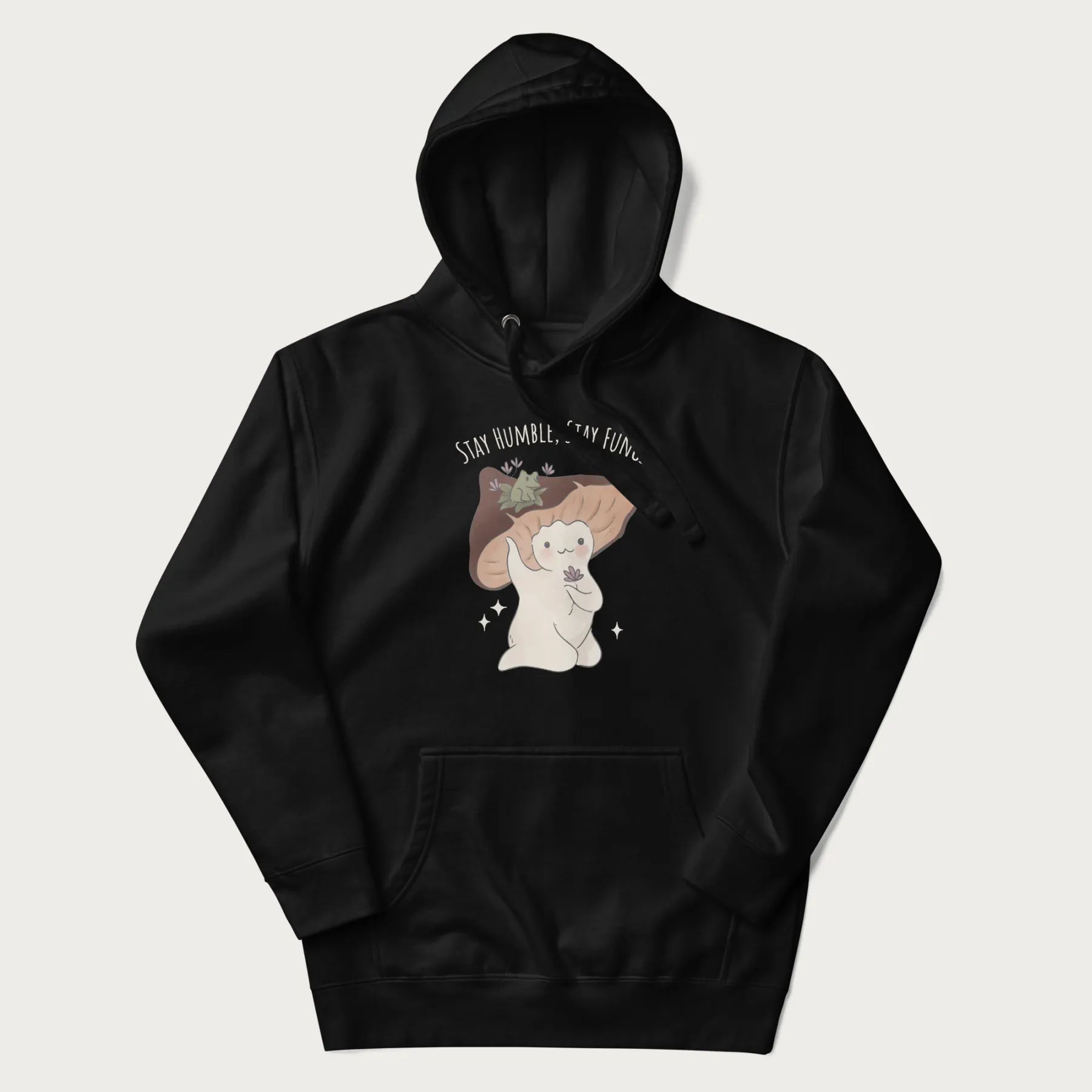 Black hoodie with graphic of a cute mushroom character holding a flower with a frog on its cap and the text 'Stay Humble, Stay Fungi' above.